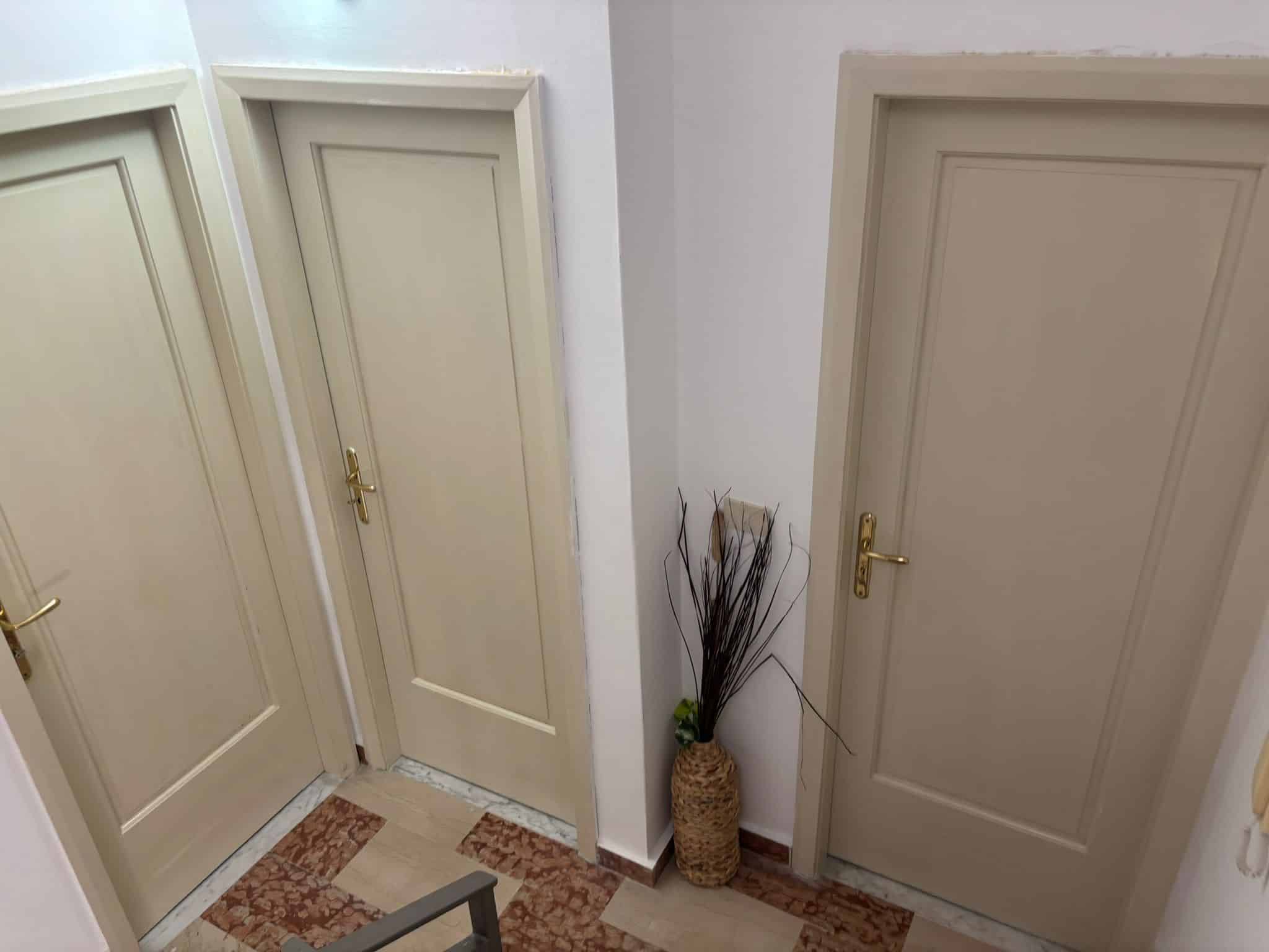 Porta in legno color crema, stile classico, con anta liscia e maniglia dorata, all'interno di un appartamento, perfetta per arredamento residenziale, con dettagli eleganti e funzionali, ambiente interno ben curato.