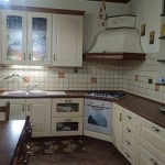 Cottura e cucina classica in stile rustico con mobili bianchi e dettagli in legno, ideale per case di famiglia o ambienti accoglienti.