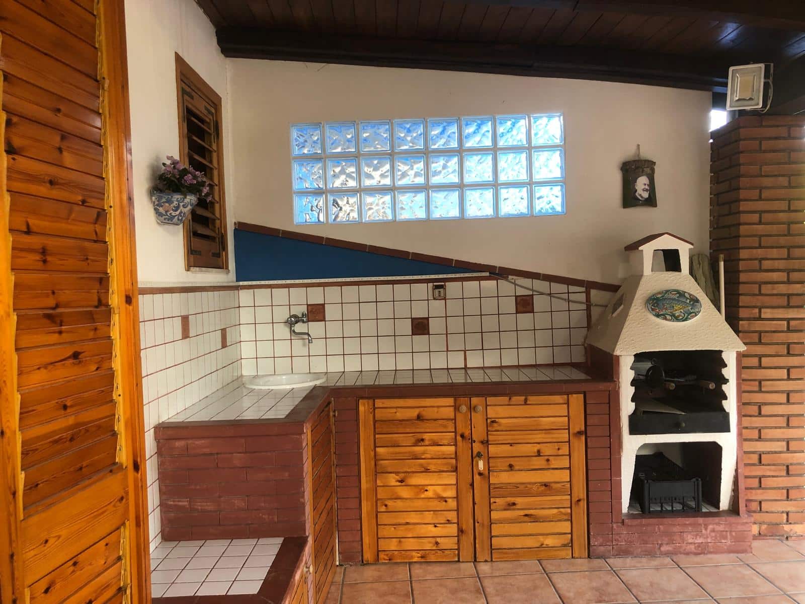 Lavello esterno in muratura bianca con forno a legna e cucina in stile rustico, perfetti per la vita all'aperto e le grigliate, in un ambiente accogliente e tradizionale.