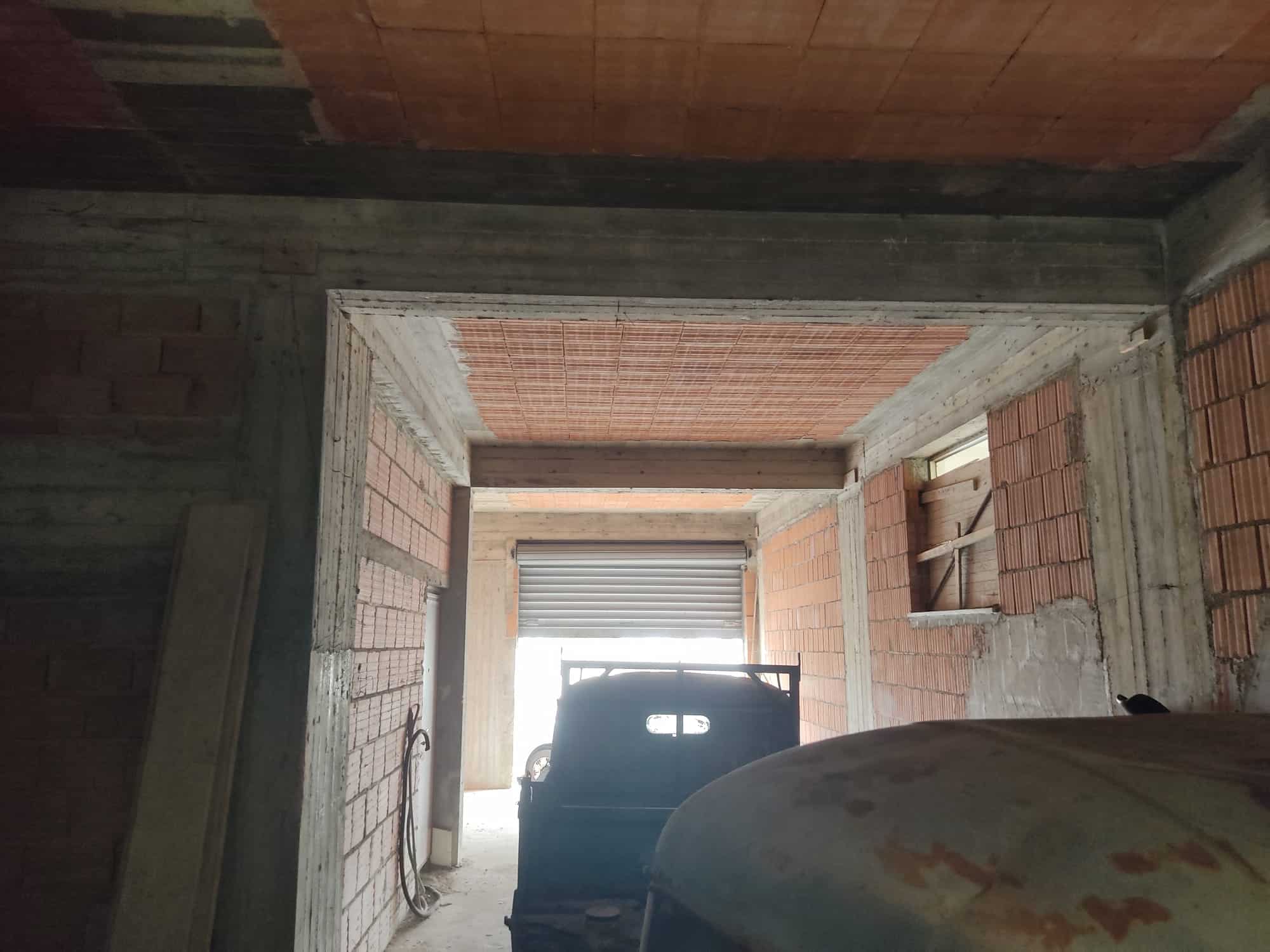 Cantiere edile in fase di costruzione di un garage o autorimessa, con struttura in mattoni e cemento, pronto per i lavori di finitura e isolamento.