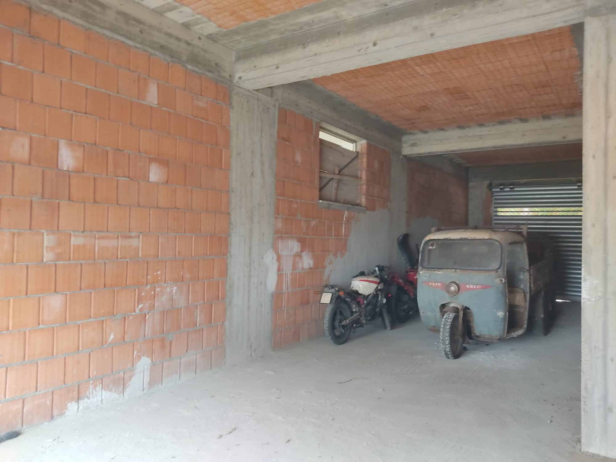 Auto in costruzione con pareti in mattoni e struttura in cemento, garage o deposito ancora in fase di completamento.