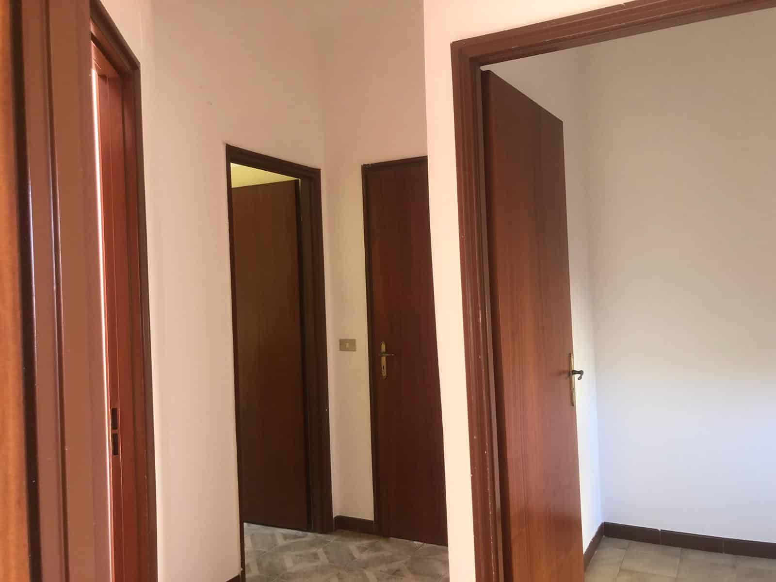 Porta ingresso in legno, stanze con porte interne in stile classico, finiture in legno, interni spaziosi, ambienti luminosi, arredamenti funzionali, casa in vendita, appartamento di qualità, NextCasa.