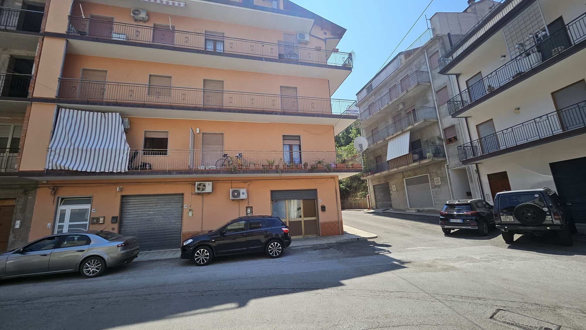 Villette residenziali con balconi, parcheggi e biciclette in una zona urbana italiana. Edifici multifamiliare con facciate in stucco e strutture di cemento, ambienti esterni in posizione centrale.