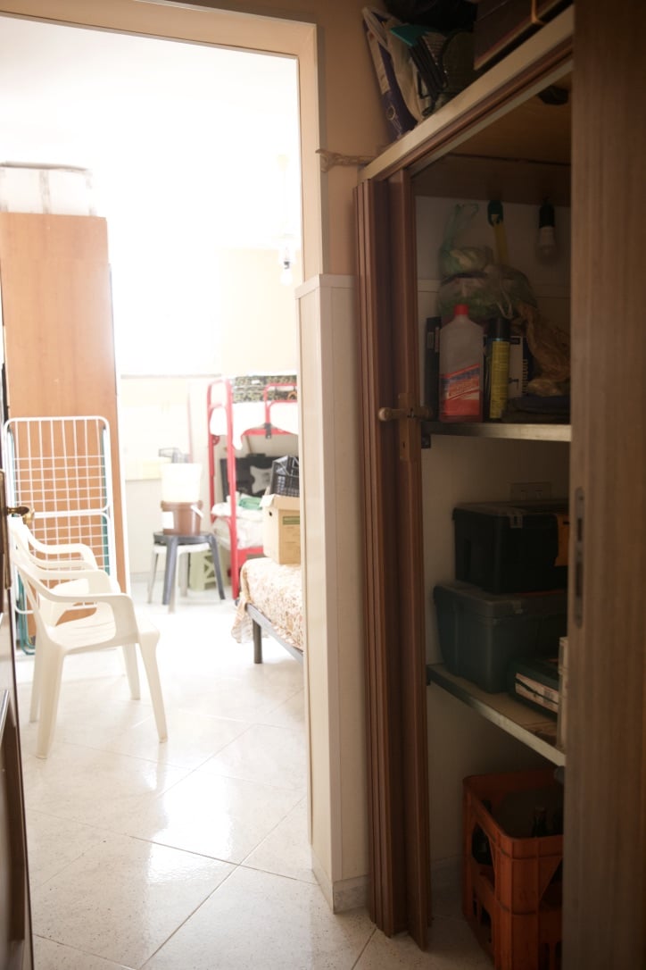 Magazzino, ripostiglio di casa, spazio di stoccaggio con scaffali e oggetti domestici, vista sulla zona giorno con sedie e arredamento, ambiente domestico ordinato e funzionale, NextCasa Italia.