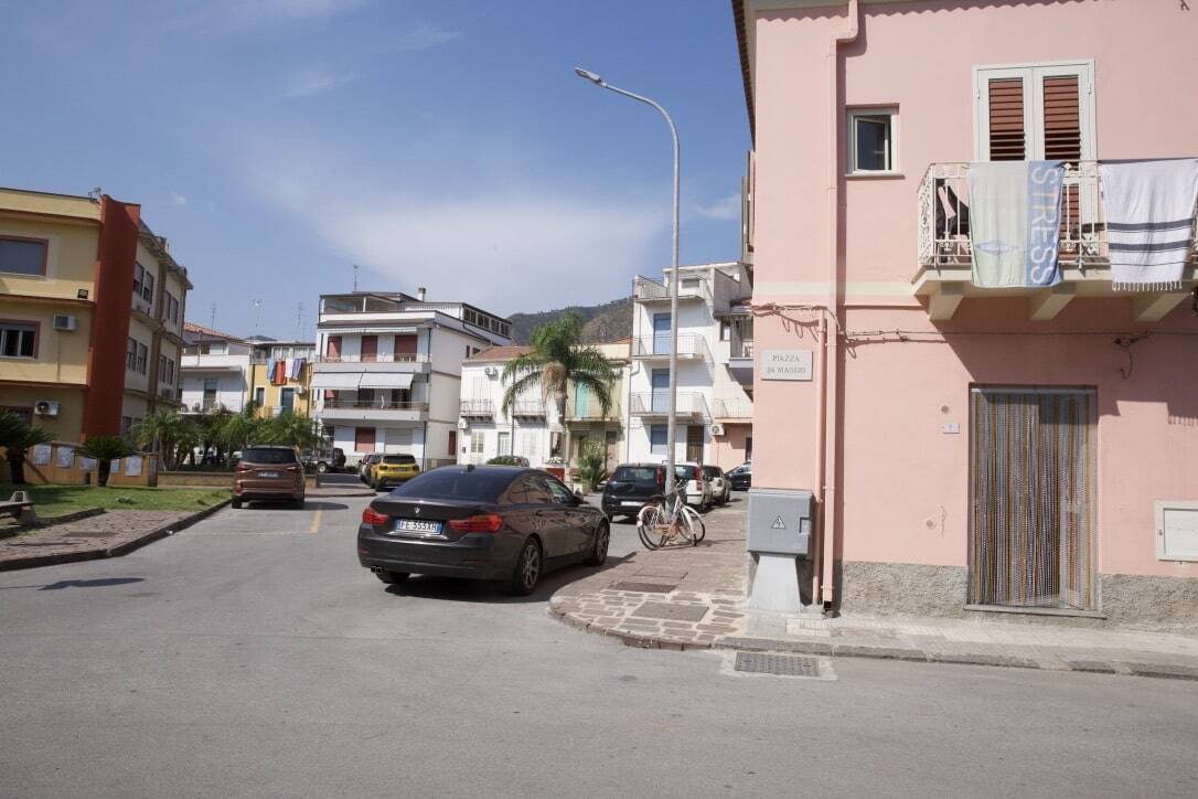 Appartamenti residenziali a Ortona, zona Piazza Mazzini, vista strada con auto parcheggiate e palazzi colorati in stile mediterraneo, cielo sereno e montagne sullo sfondo.