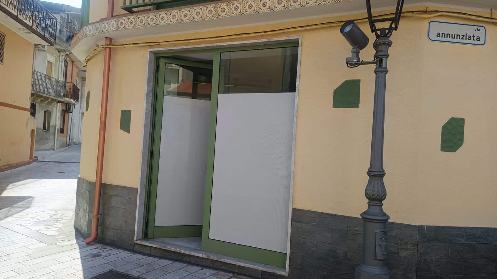 Porta automatizzata per negozio o attività commerciale in zona urbana, installata su strada con illuminazione pubblica, struttura moderna e funzionale.
