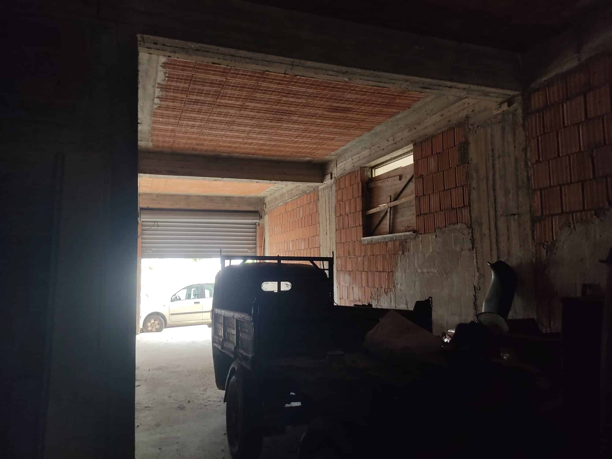 Autore; immobile in costruzione con pareti in mattoni e garage, immagine di un garage in fase di costruzione, con un'auto parcheggiata e struttura ancora grezza.