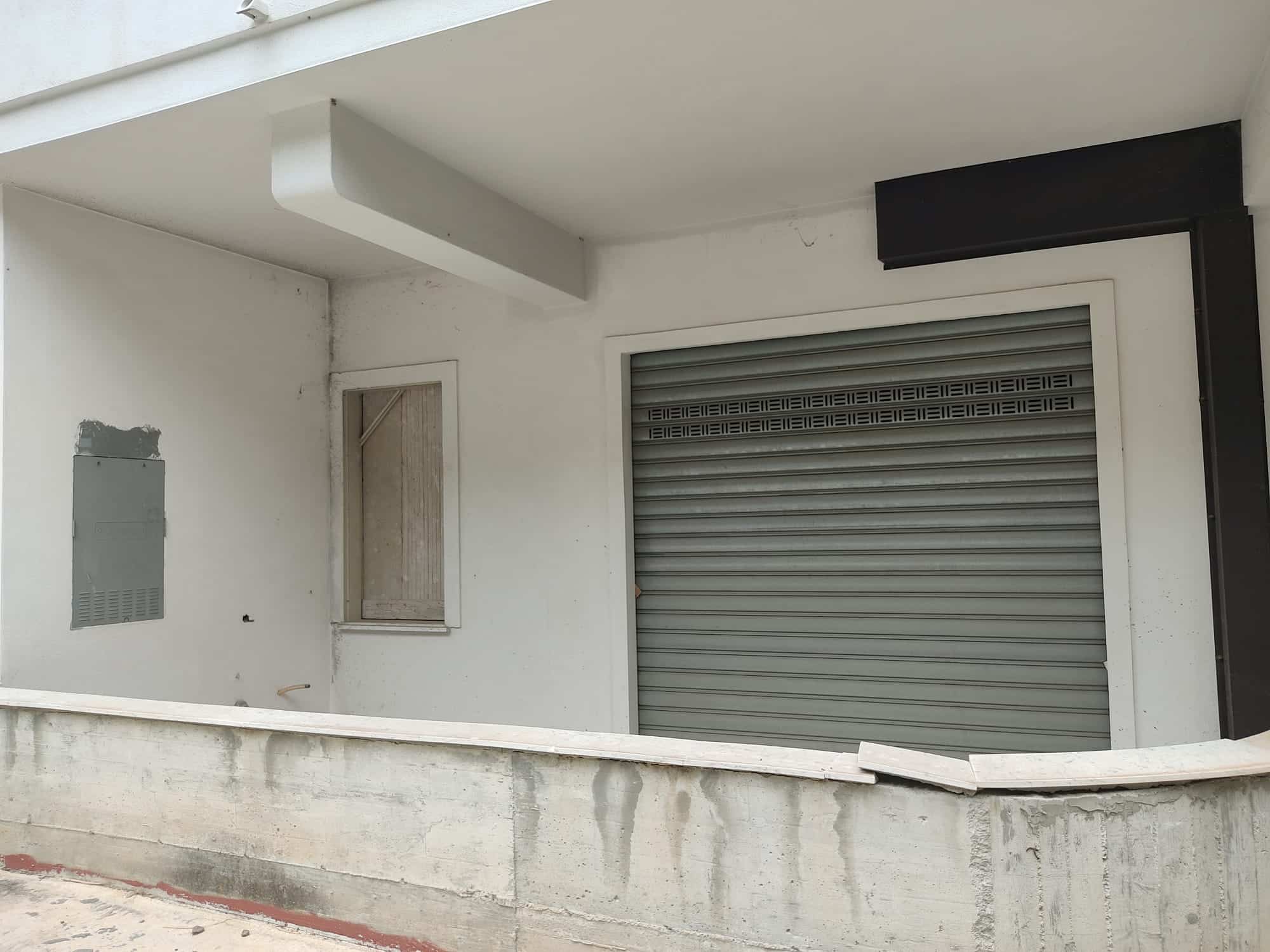 Vano garage con porta avvolgibile e finestra su edificio in fase di costruzione, stile moderno e funzionale, ideale per immobili residenziali o commerciali.