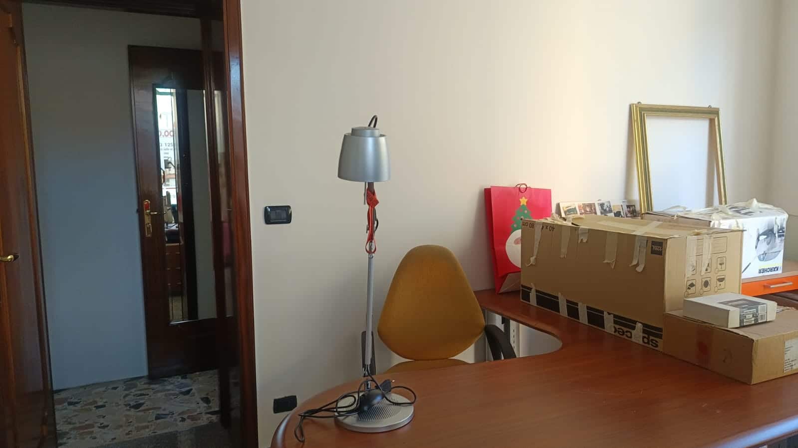 Scaffale di cartone per imballaggi e mobili, con un quadro cornice dorata e una shopping bag natalizia, in un ambiente domestico durante il trasferimento o l'organizzazione di casa.