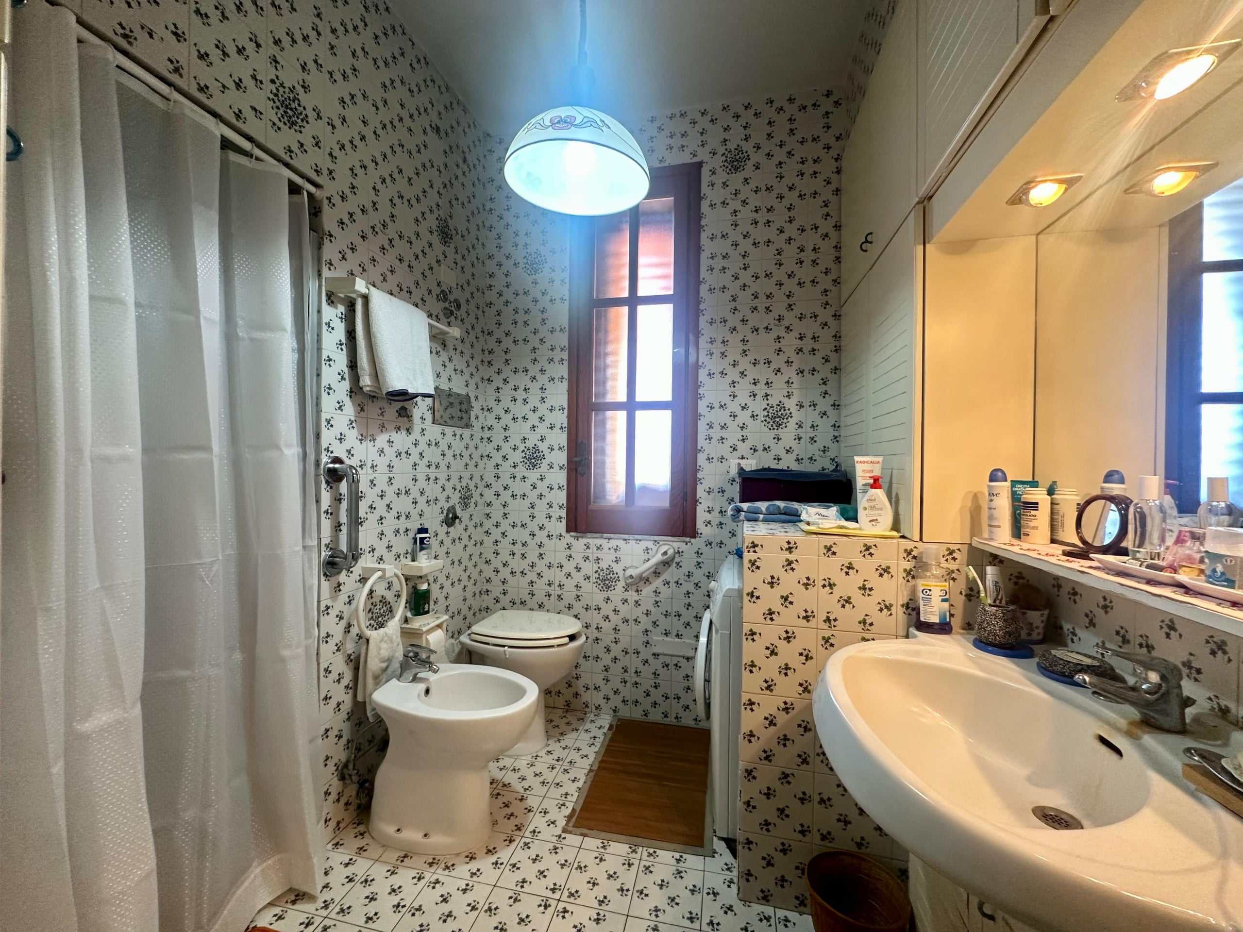 Lavabo e servizi in bagno con piastrelle decorative, finestra con luce naturale, soprattutto caratterizzato da dettagli vintage e funzionalità moderne, ideale per una casa accogliente.