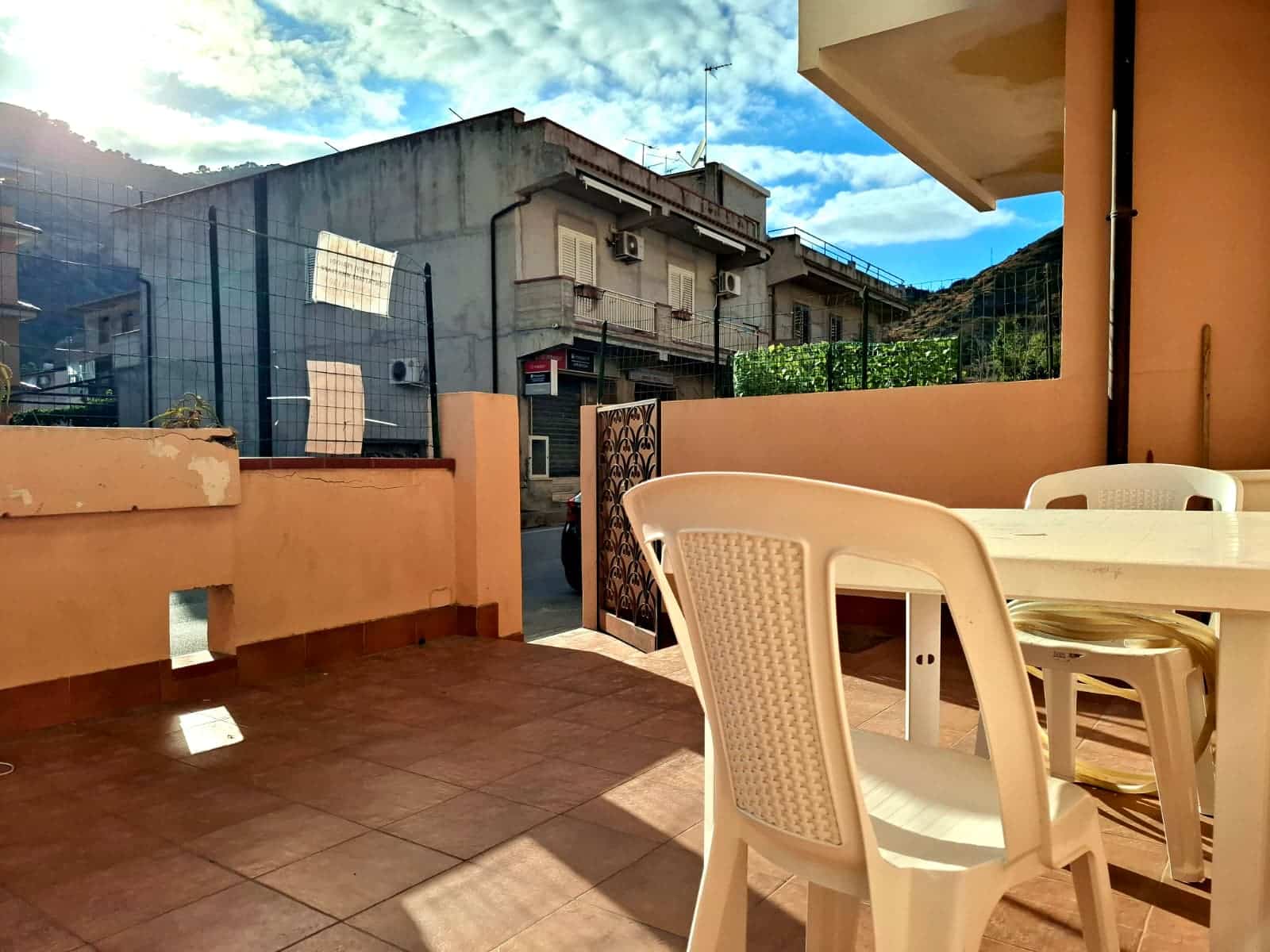 Veranda con spazio esterno arredato, vista sulle abitazioni vicine, ideale per relax e convivialità, in zona residenziale vicino a servizi, con pavimentazione in gres.