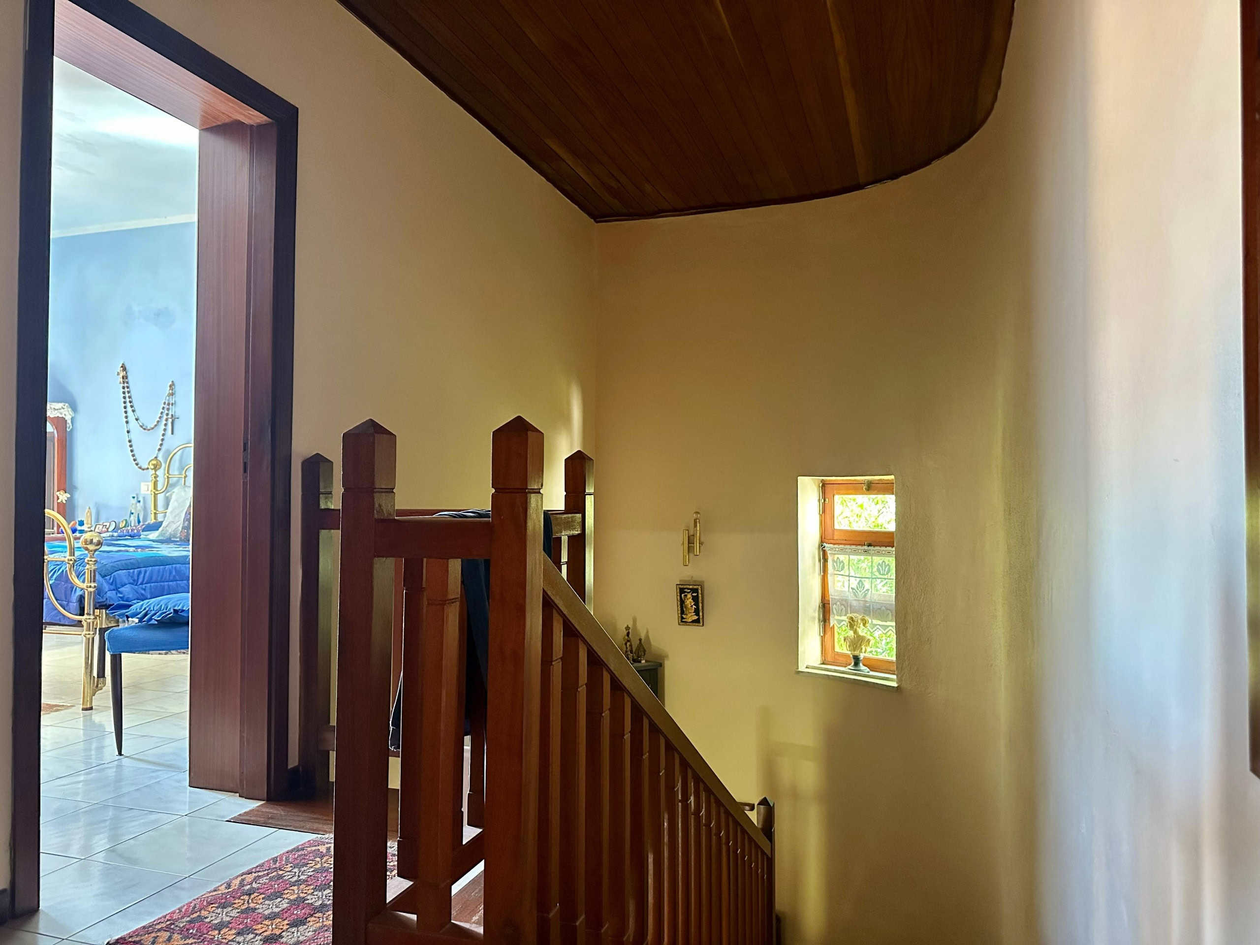 Scalinata in legno con ringhiera in stile classico, ingresso a un piano superiore di casa in stile tradizionale italiana, illuminazione naturale, pareti di colore chiaro, dettagli di arredamento rustico e accogliente, atmosfera calda e familiare, stile casa di campagna italiana.
