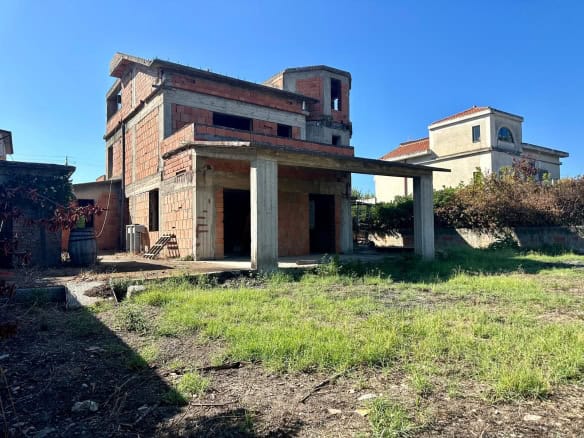 Casa in costruzione con struttura in cemento e mattoni, progetto di nuova abitazione a NextCasa. Edificio ancora in fase di completamento, con spazio esterno e giardino annesso.