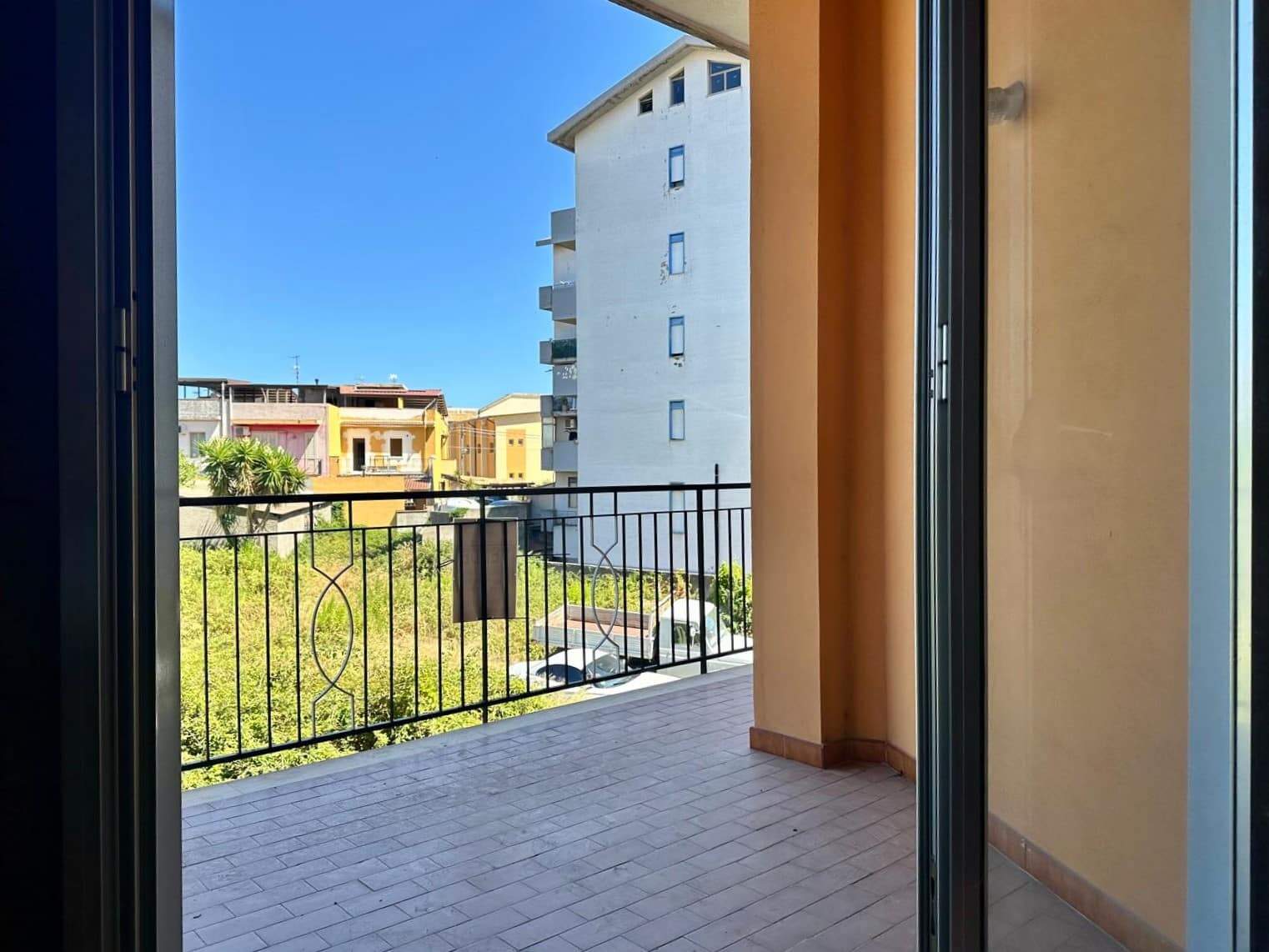 Balcone con vista sul tetto di edifici residenziali, ambiente luminoso e spazioso, ideale per spazi esterni e relax in appartamenti vicino al centro.