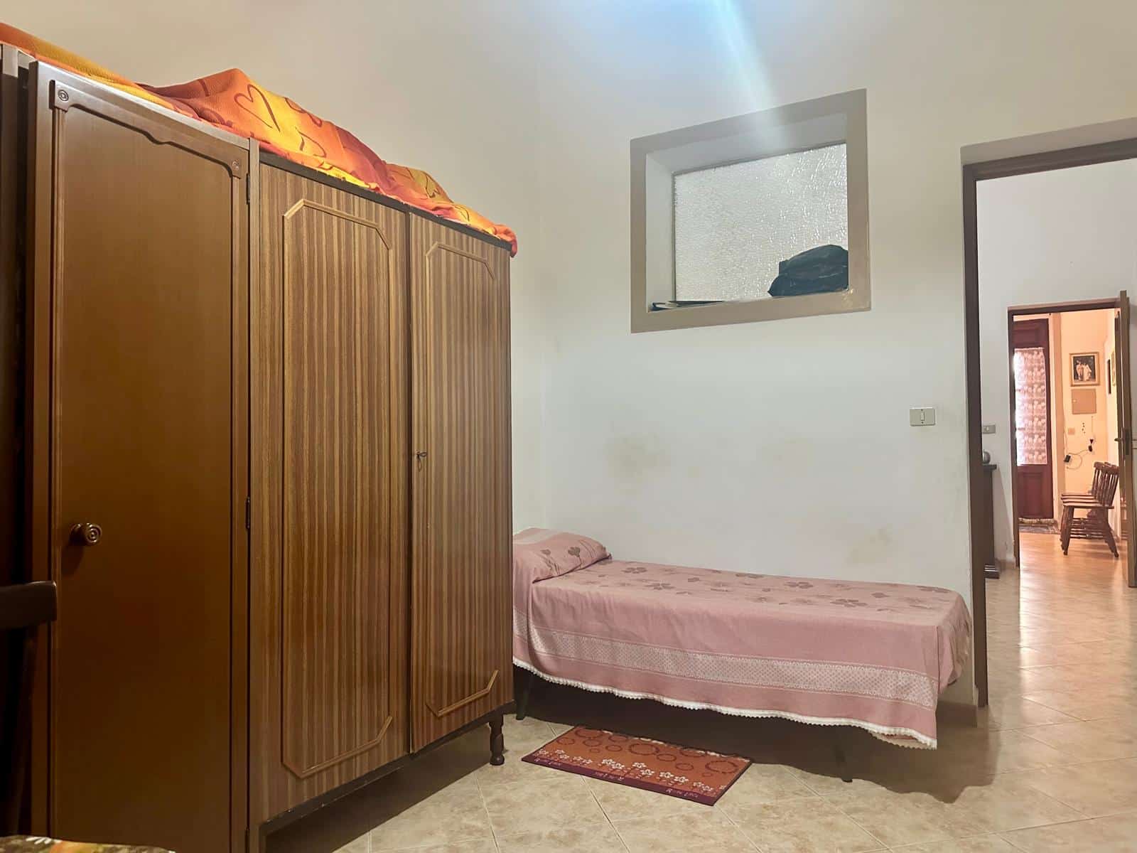 Armadio in legno, stanza singola con letto matrimoniale, arredamento semplice, finestra con ottima illuminazione naturale, spazio abitativo tranquillo, casa in vendita NextCasa.