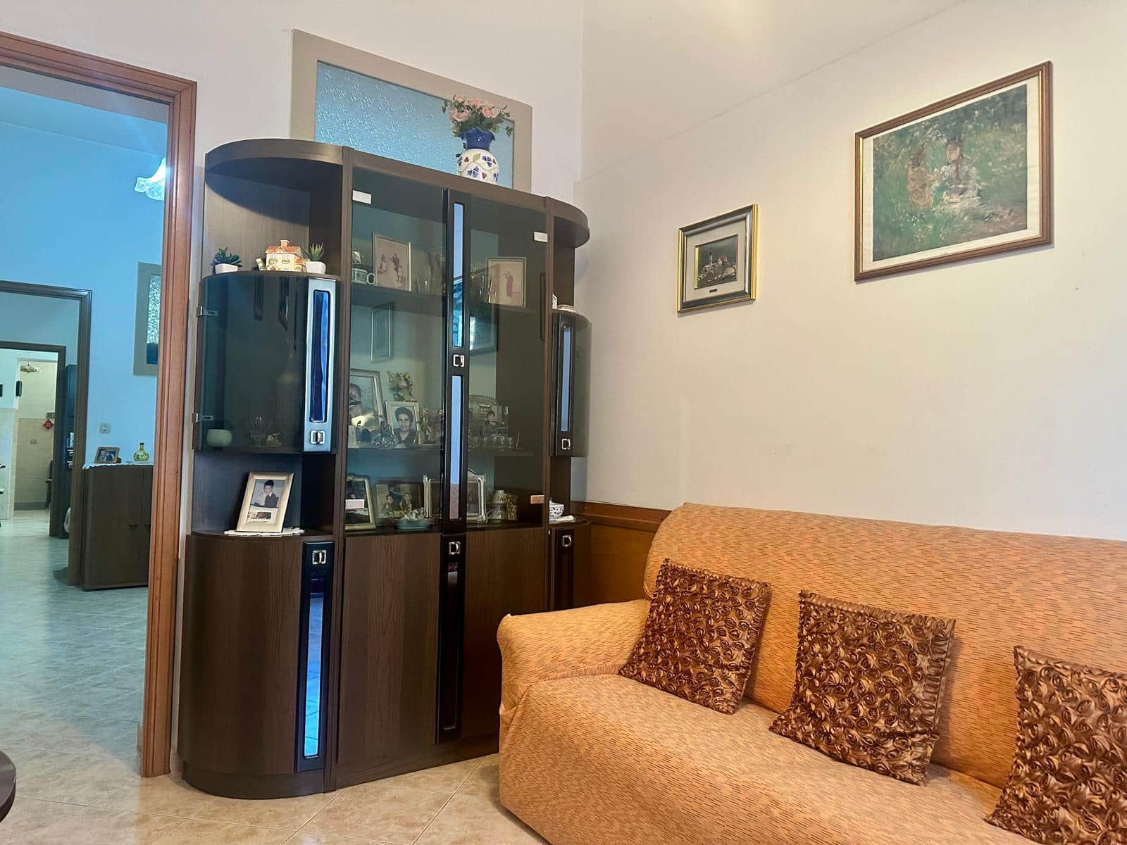 Vendita appartamento NextCasa, soggiorno con mobile antico, pareti decorate, dettagli classici e atmosfera accogliente, ideale per vivere in comodità.