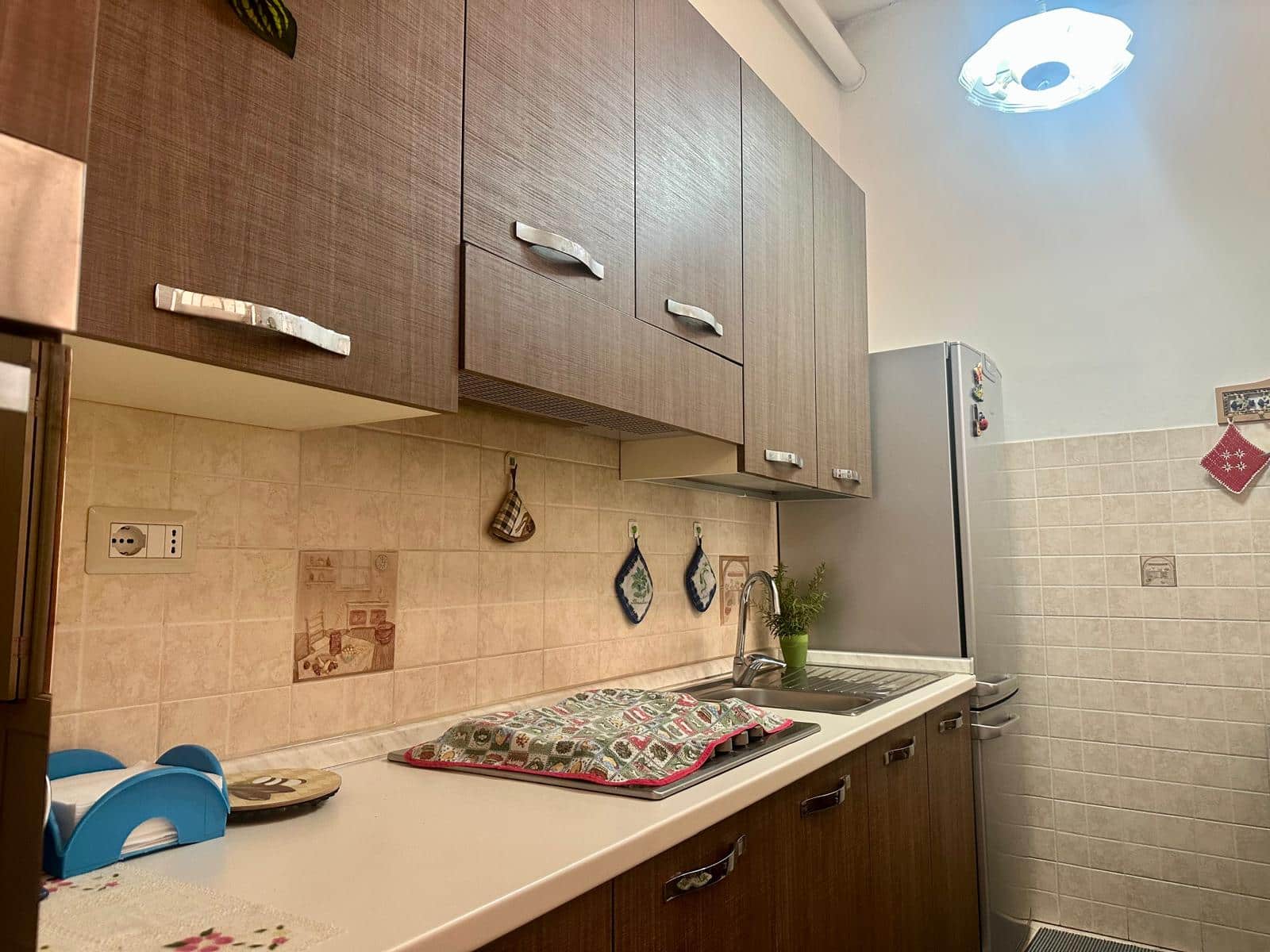 Elegante cucina moderna con mobili in legno, piano di lavoro e dettagli decorativi, ideale per cucinare e trascorrere momenti conviviali in casa.