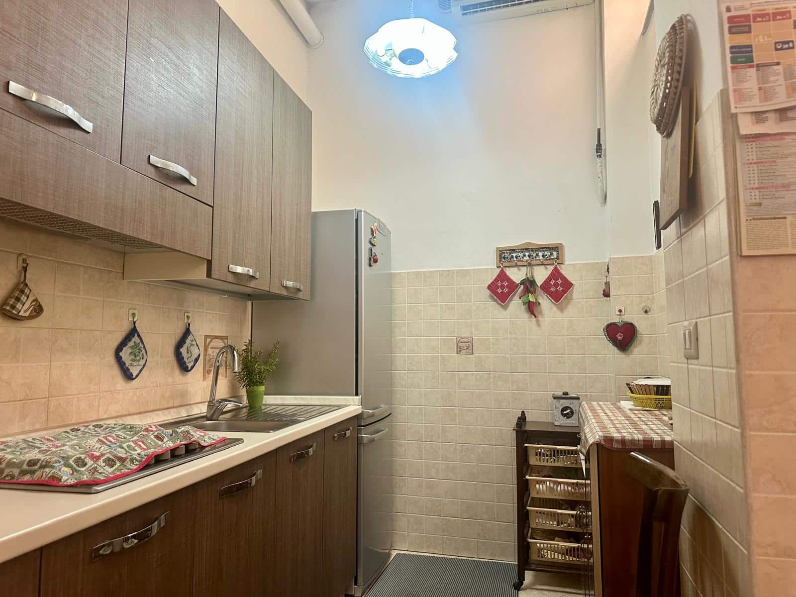 Lavanderia in stile tradizionale con mobili in legno chiaro, frigorifero, decorazioni natalizie e stoviglie, ambiente funzionale e accogliente all’interno di una casa.