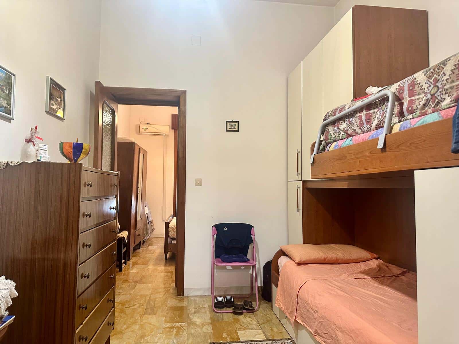 Camera da letto con letti a castello, armadio e mobili in legno, atmosfera domestica e accogliente. Ideale per case o appartamenti in affitto a NextCasa, soluzione funzionale e comoda.