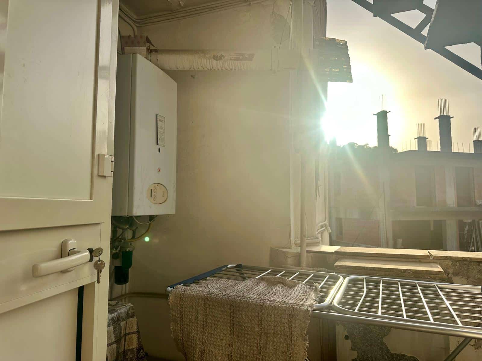 Lavanderia su balcone con asciugatrice, stendibiancheria e vista sul tramonto, soluzione funzionale per appartamento in centro città.
