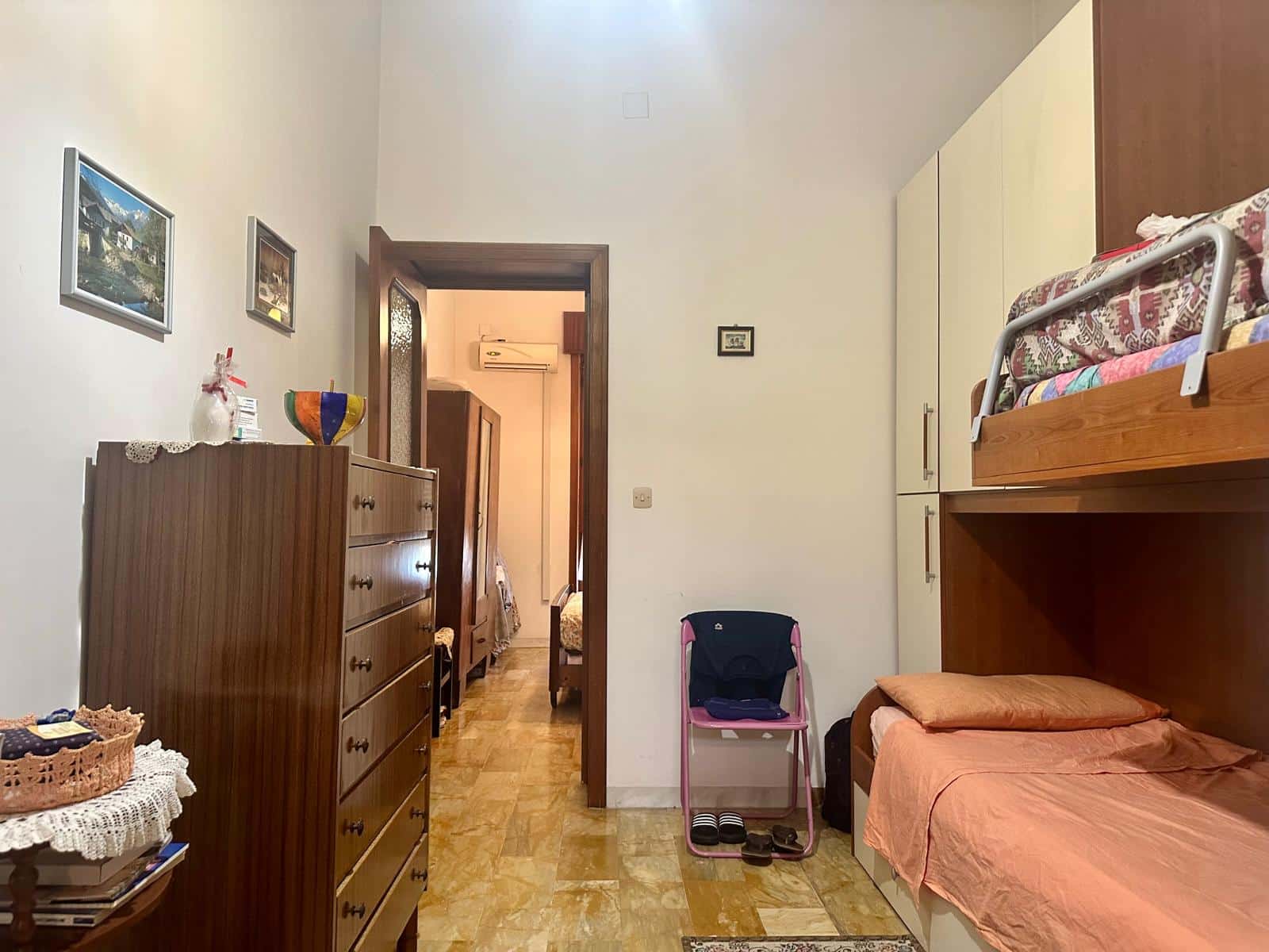Armadio a muro e letto a soppalco in una camera da letto con arredi in legno e decorazioni classiche. Ambiente accogliente e funzionale, ideale per spazi ridotti.