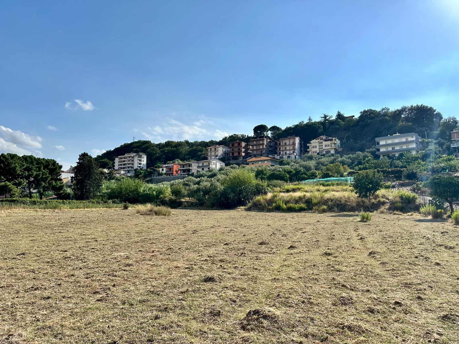 Campagna con case moderne su collina, panorama naturale, esempio di immobili residenziali di lusso vicino alla natura, vista di case eleganti e verdeggiante, ambiente tranquillo e soleggiato, ideali per investimento immobiliare NextCasa.
