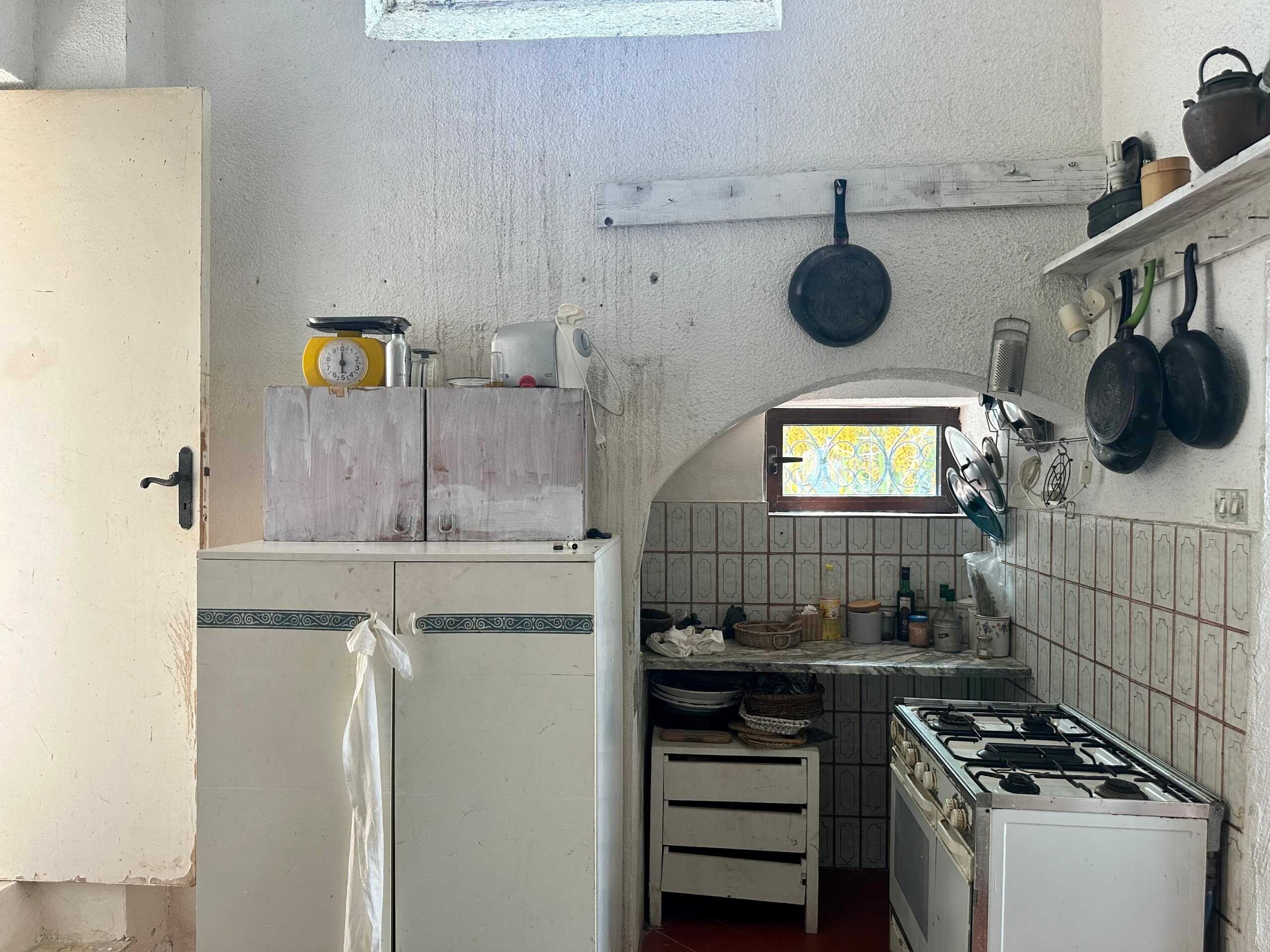 Vecchia cucina rustica con mobili da cucina e pentole sospese, ambiente semplice e caratteristico, perfetto per creare un'atmosfera tradizionale e accogliente nella casa.