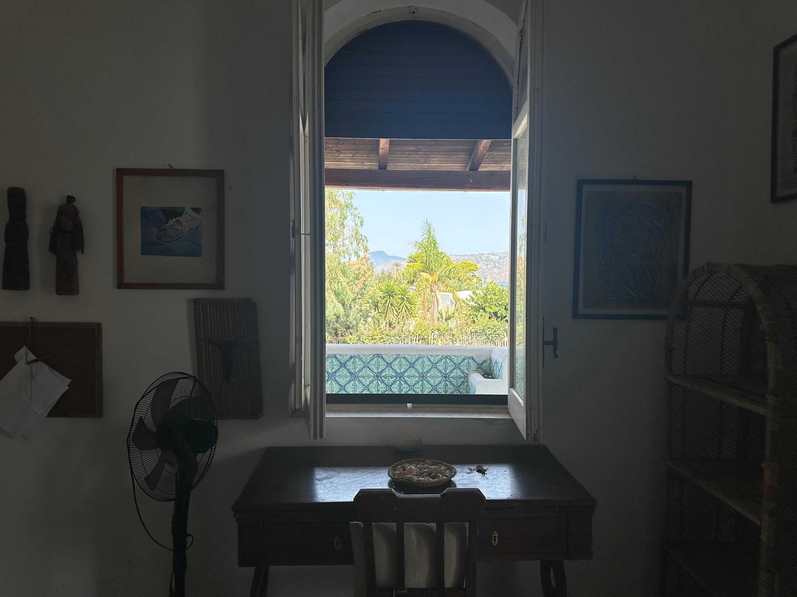 Finestra aperta con vista su terrazza e paesaggio naturale, illuminazione naturale, arredo semplice, atmosfera rilassante, case vacanza, stile mediterraneo, NextCasa, immobile in affitto o vendita.