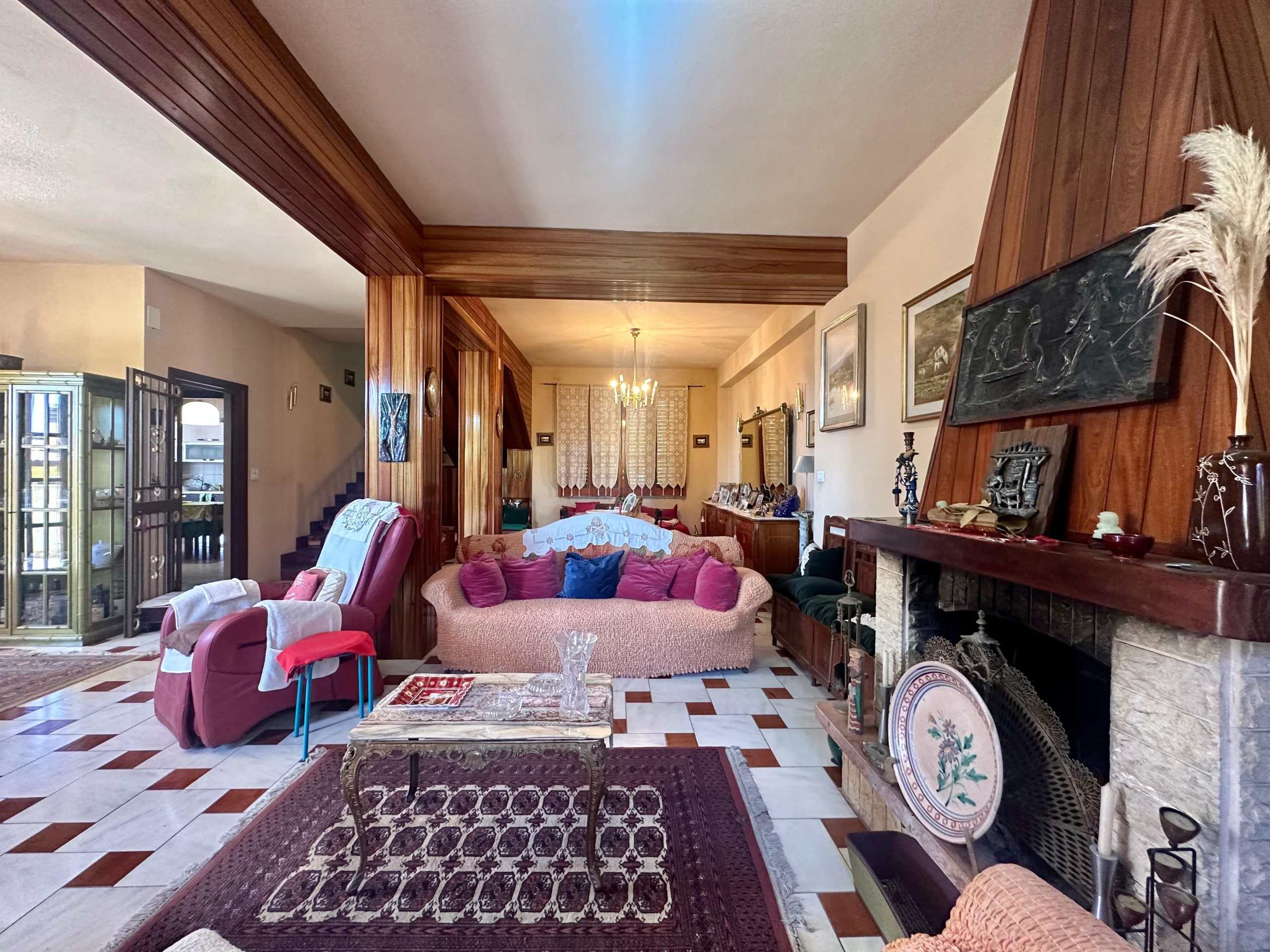 Accogliente soggiorno con camino in stile classico, divani colorati e dettagli d'antiquariato, ideale per il relax e l'intrattenimento in una casa spaziosa e ben arredata.