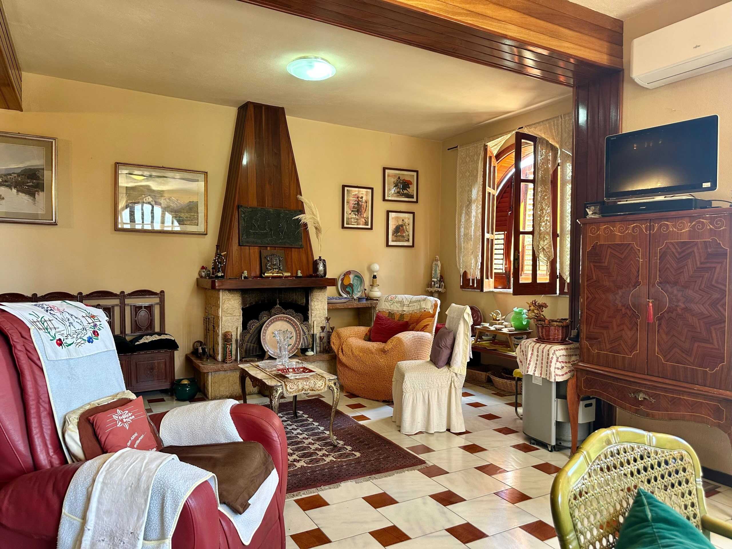 Ingresso di soggiorno accogliente con camino in pietra, mobili in legno anticato, tende leggere alle finestre e decorazioni classiche, luminoso e confortevole ambiente in stile tradizionale.