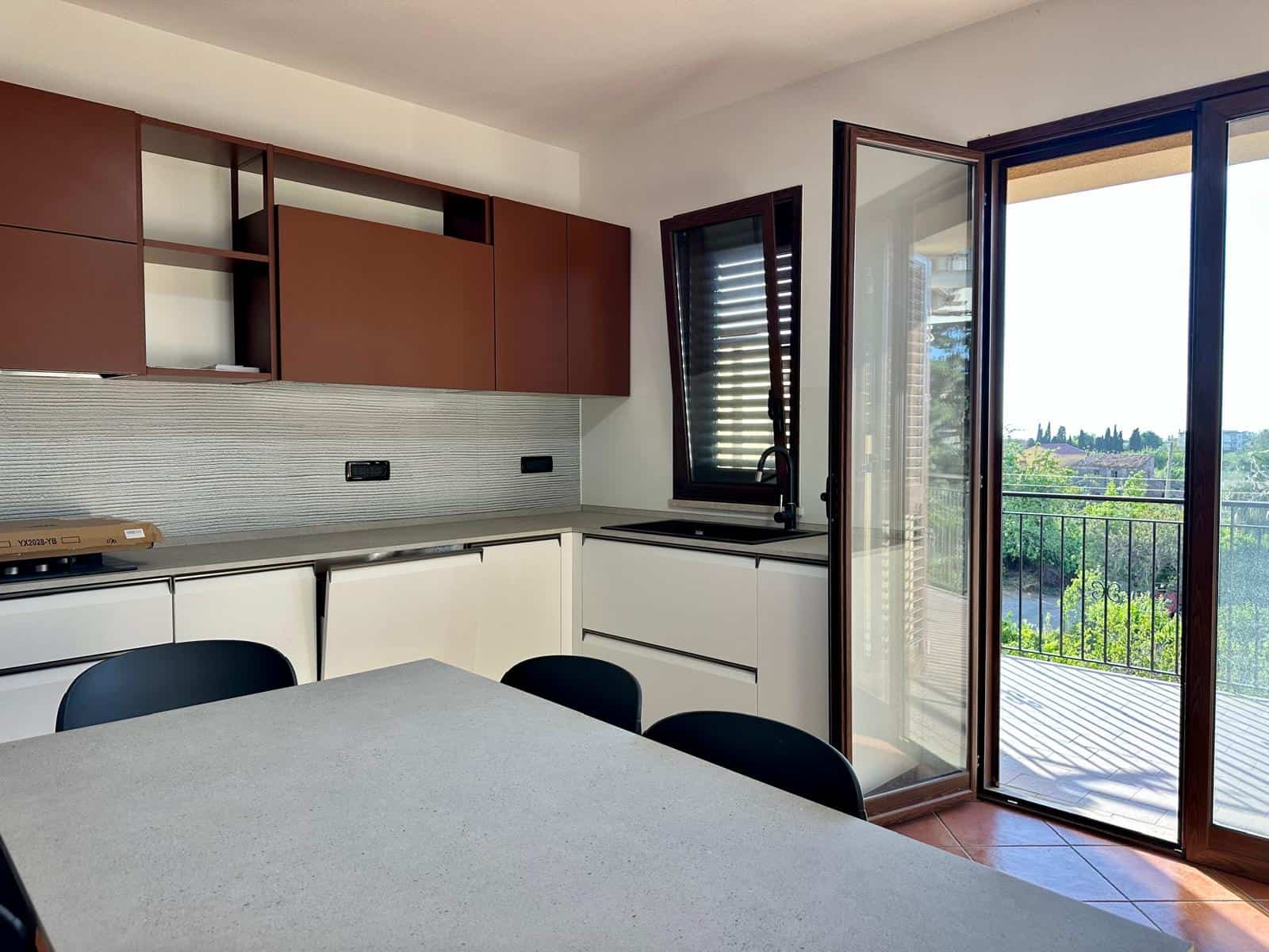 Cucina moderna con mobili in legno e balcone con vista panoramica, ambiente luminoso e accogliente.