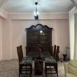 Arredo sala da pranzo elegante con mobile antico in legno scuro, tavolo in cristallo e sedie con rivestimento animalier, in una zona luminosa con tende leggere e pavimento in mosaico.