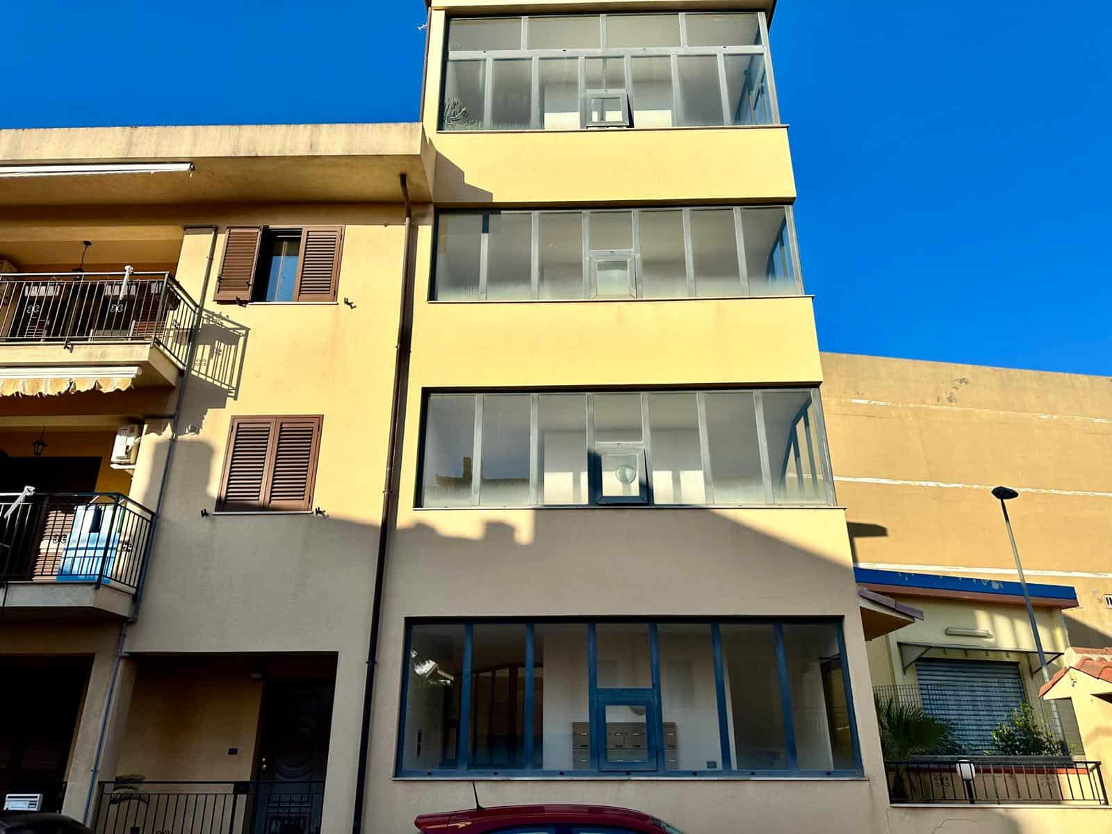 Balcone e facciata di un edificio residenziale moderno con ampie vetrate e balconi, sotto un cielo azzurro, rappresentando un esempio di design contemporaneo e comfort abitativo.