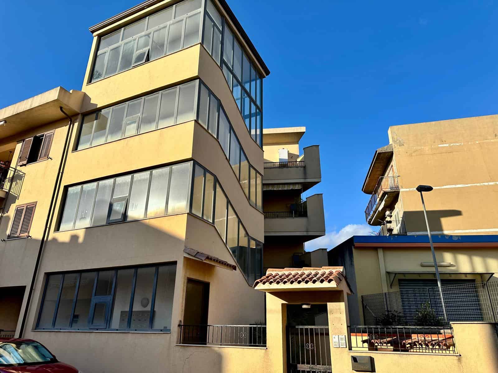 Balcone e facciata di un edificio residenziale moderno con ampie finestre e balconi, situato in un quartiere urbano soleggiato, rappresentando soluzioni immobiliari di alta qualità a NextCasa.