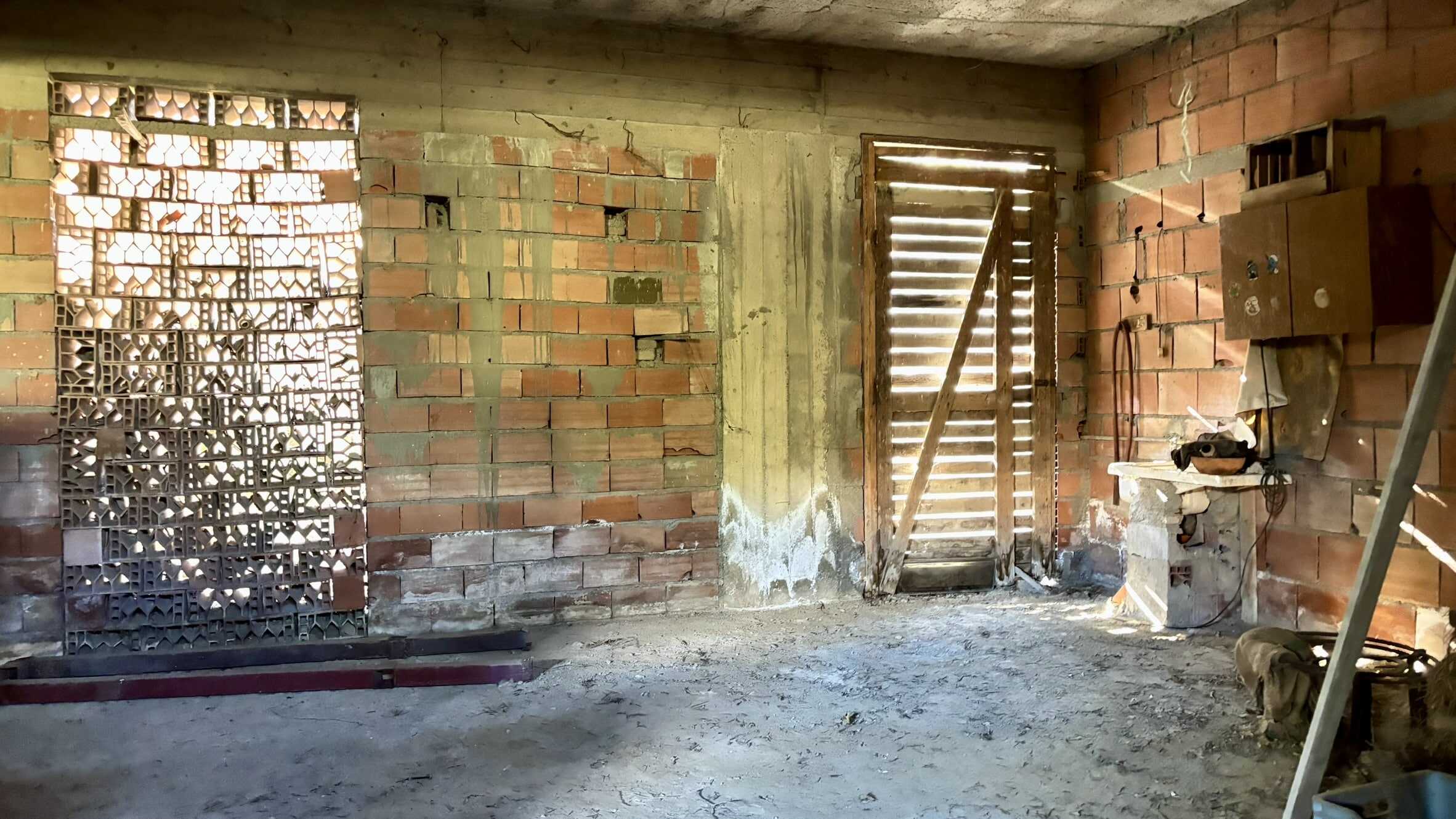 Scaffale in mattoni forati, porta in compensato con fessure, pareti in mattoni rossi non finirti, oggetti da cantiere, ambiente di costruzione o ristrutturazione.