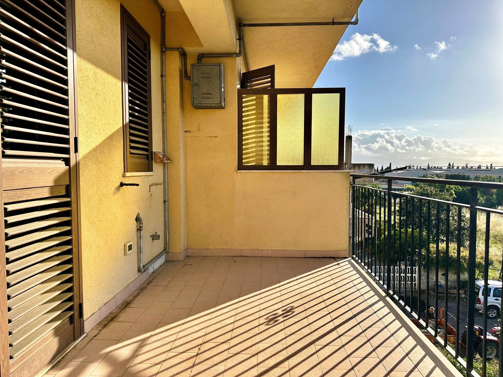 Ampia terrazza soleggiata con vista panoramica sulla città, balcone in stile moderno con ringhiera in metallo e pavimento in piastrelle beige, ideale per relax e momenti all'aperto.