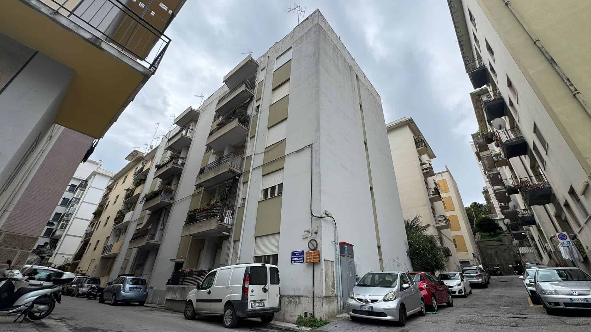 Vecchio edificio residenziale in centro città con balconi e parcheggio, vista dell'architettura urbana e delle abitazioni.