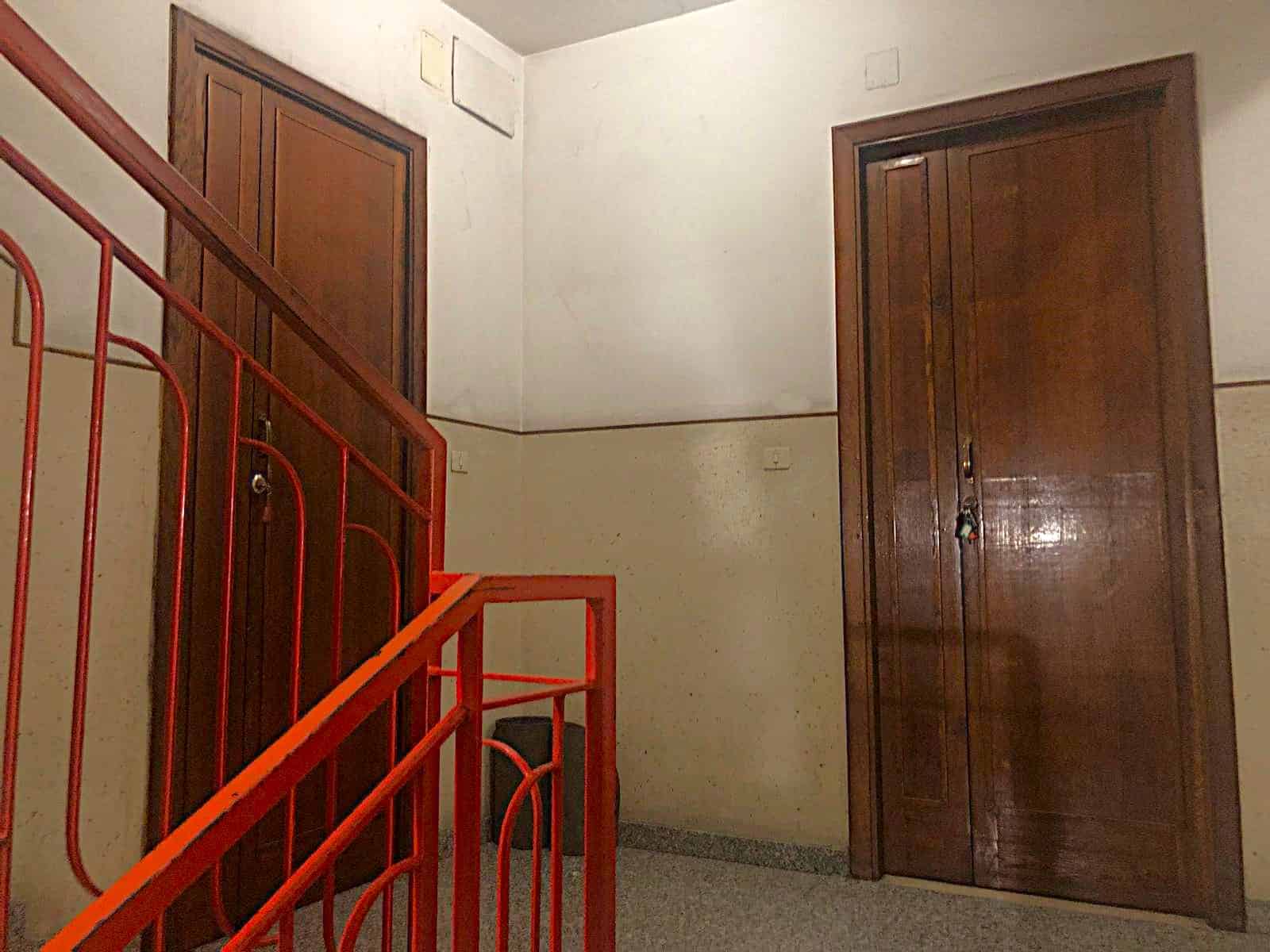 Porte in legno massello, scala in ferro e porte di armadi in legno, spazio interno di una casa o appartamento con dettagli architettonici classici e funzionali.