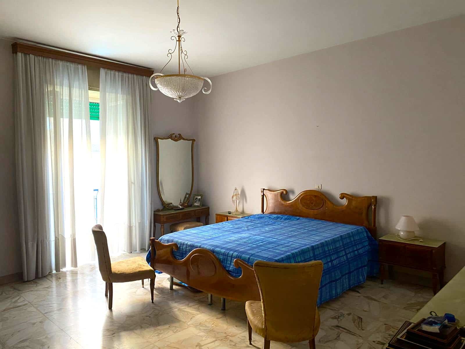 Letto matrimoniale in stile classico con guardaroba e comò, arredo soggiorno ospitale e luminoso, circondato da mobili vintage e decorazioni eleganti, ideale per camera da letto tranquilla e accogliente.