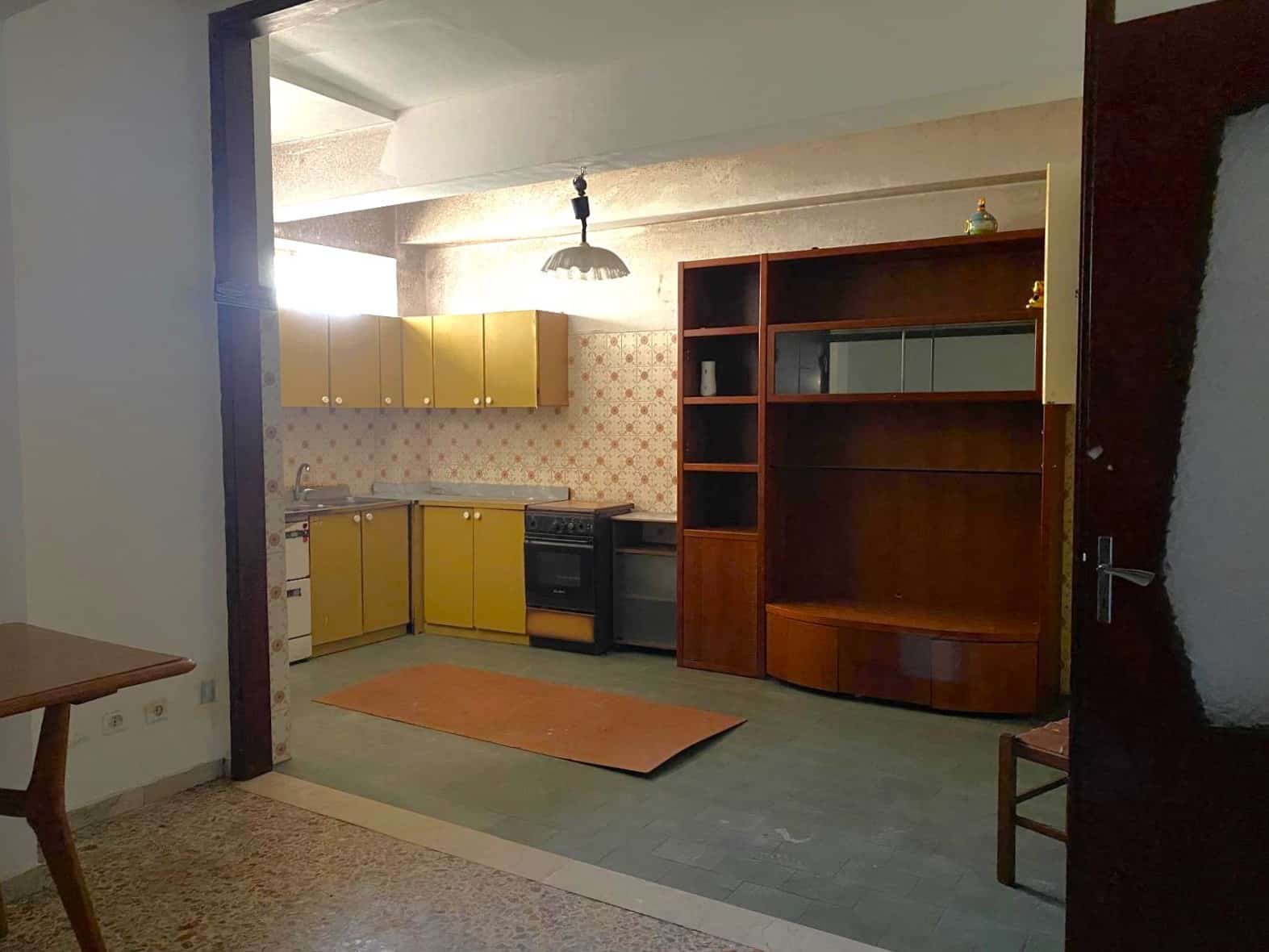Stanza cucina abitabile in un appartamento con elementi d'epoca, mobili colorati e pareti rivestite con carta da parati vintage, ideale per chi cerca un'immobile con charme retrò e spazi funzionali.