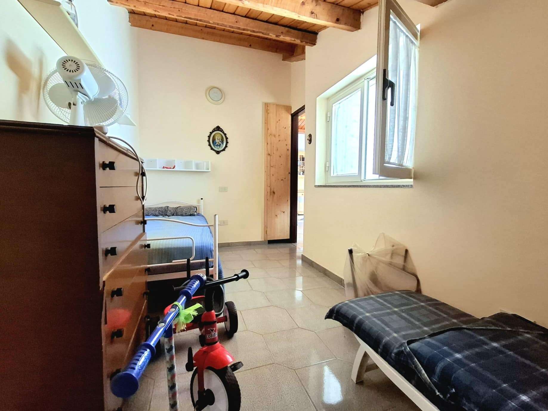 Spazio camera da letto con lettino, armadio e finestra luminosa per ambienti di case NextCasa. Interno accogliente e funzionale, ideale per residenze familiari o camere per bambini.