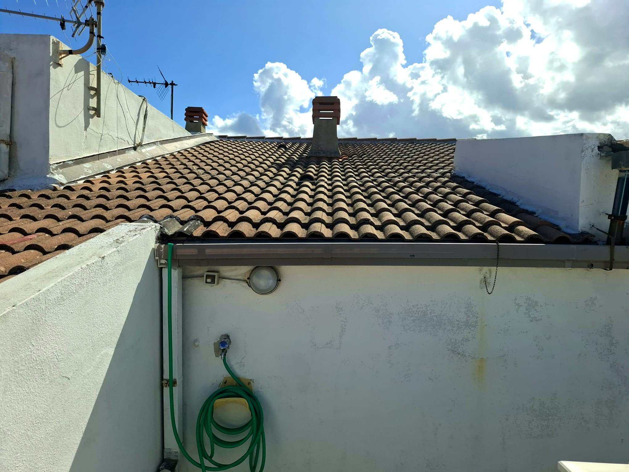 Tetto con tegole in terracotta e camino in mattoni, vista cielo azzurro con nuvole, case di charme e ristrutturate, appartamenti accoglienti, ristrutturazione edilizia, servizi immobiliari NextCasa.