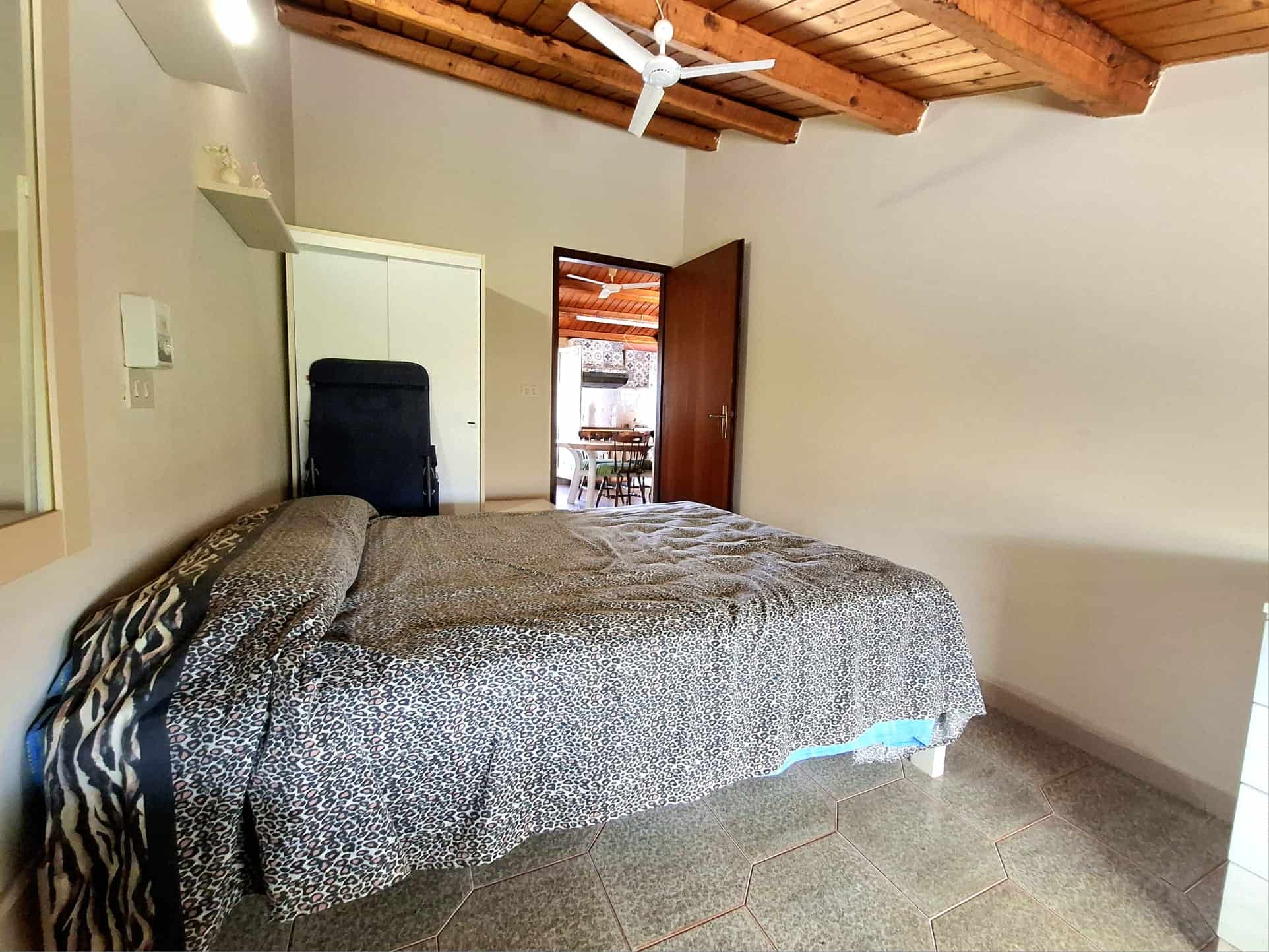 Camera da letto accogliente con mobili pratici, pareti chiare, soffitto in legno e pavimento in ceramica, ideale per soggiorni confortevoli e riposanti. Perfetta soluzione di alloggio in stile rustico moderno.