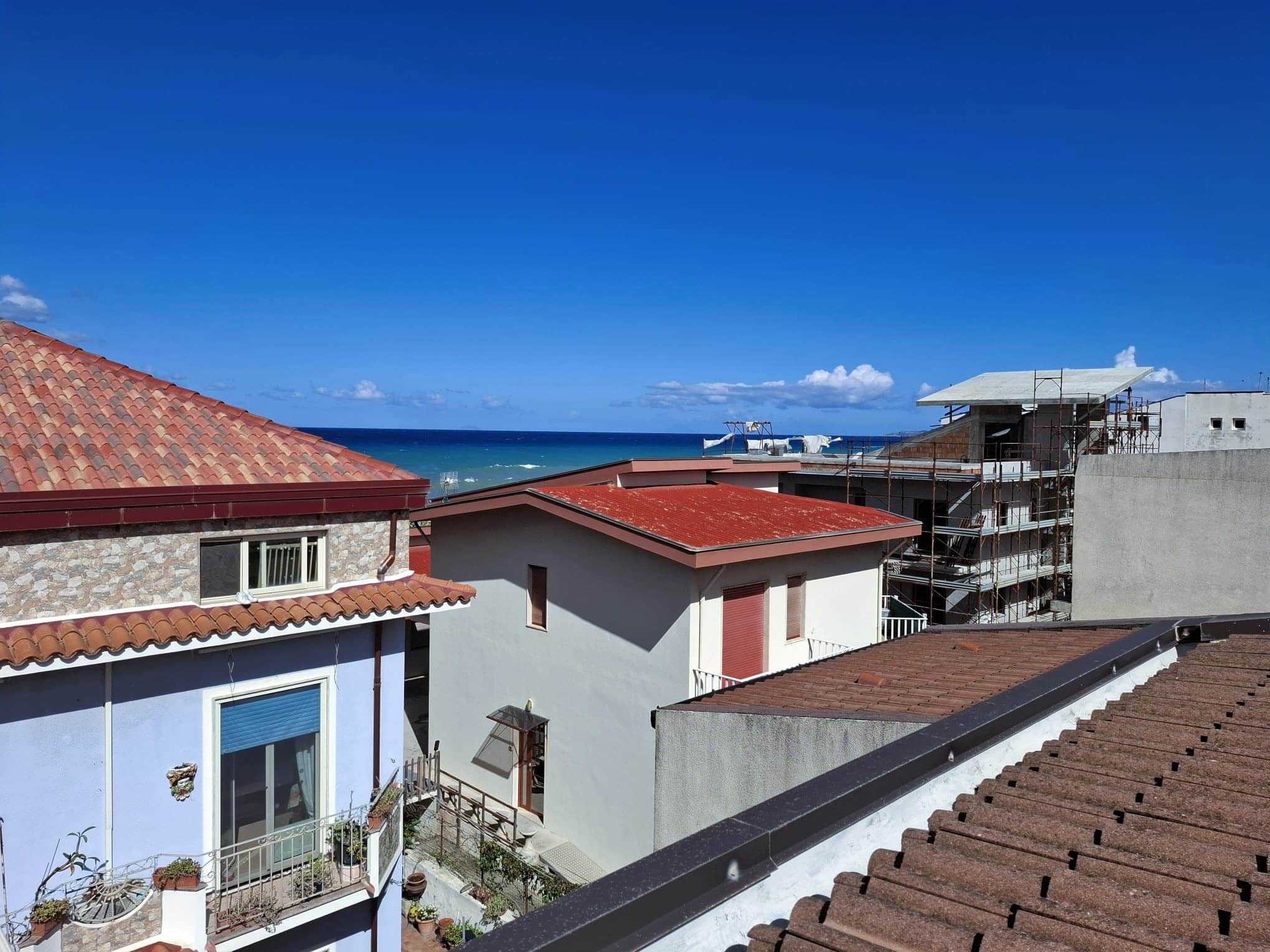 Veduta mare dal terrazzo di un appartamento a Jesolo, case con tetti in terracotta e costruzione in corso, vista sulla costa adriatica da una località balneare in Italia.