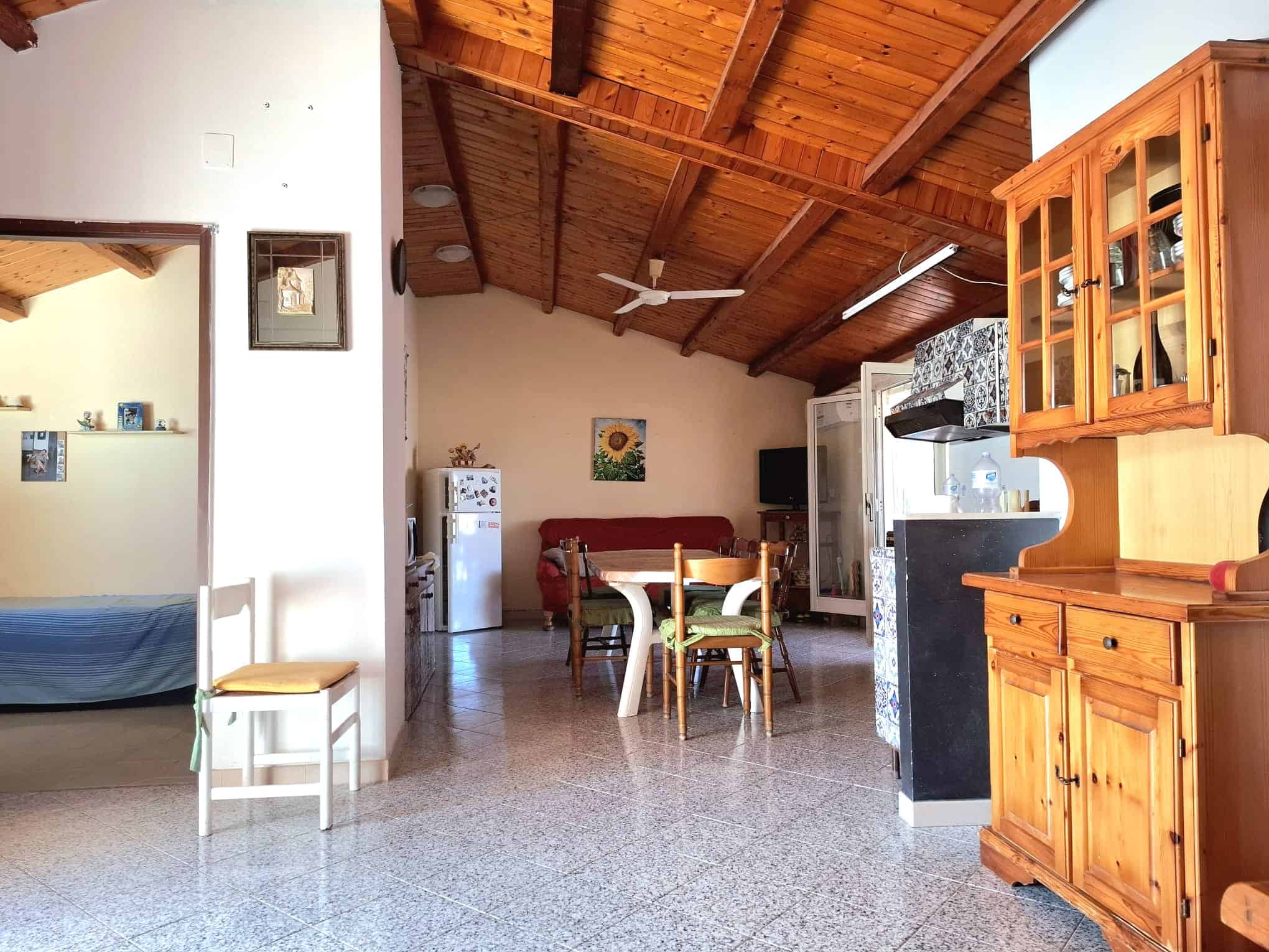 Casetta in affitto con interni accoglienti e arredi in legno, cucina con zona pranzo, soggiorno luminoso e camera da letto, ideale per soggiorni in relax. Esposta con soffitto in legno, arredi in stile rustico e elementi funzionali.