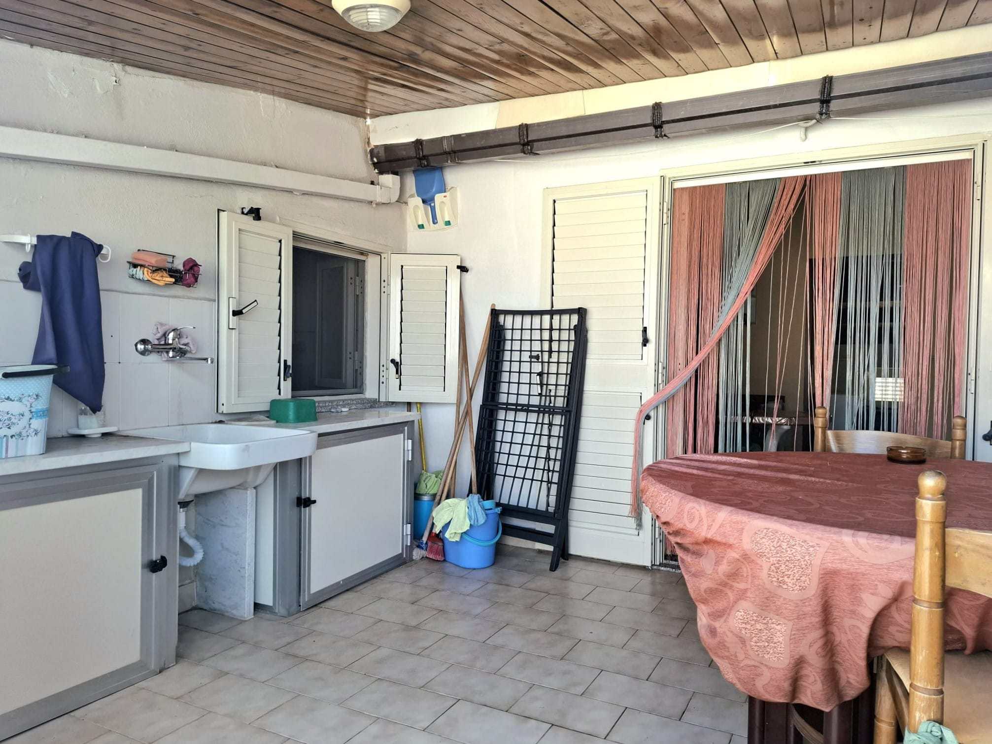 Lavanderia esterna con finestre e zona di lavoro con lavabo, attrezzi e tables, ambiente funzionale e pratico per le faccende domestiche all'aperto.