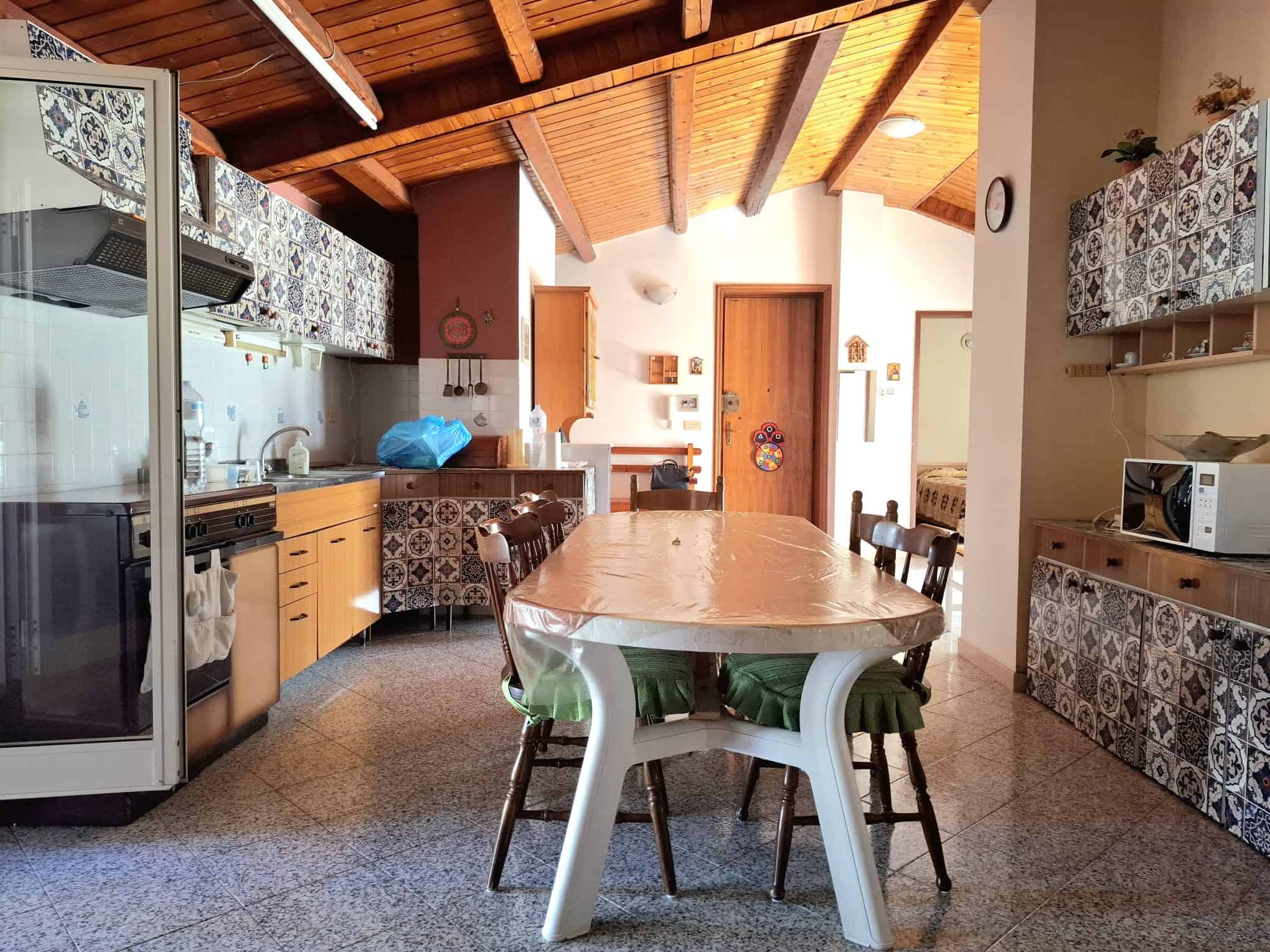 Rustico con cucina in stile tradizionale con mobili in legno, piastrelle decorative, tavolo da pranzo e soffitto in legno, ideale per chi cerca una casa accogliente e autentica.