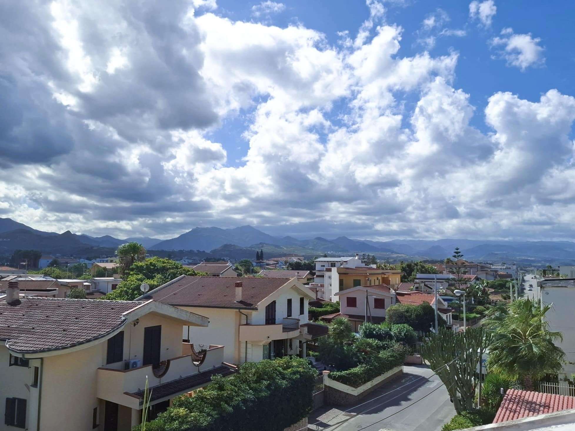 Vista panoramica sulle case residenziali con montagne sullo sfondo, cielo nuvoloso e atmosfera tranquilla, ideale per un'agenzia immobiliare come NextCasa per promuovere proprietà in zone panoramiche e residenziali.