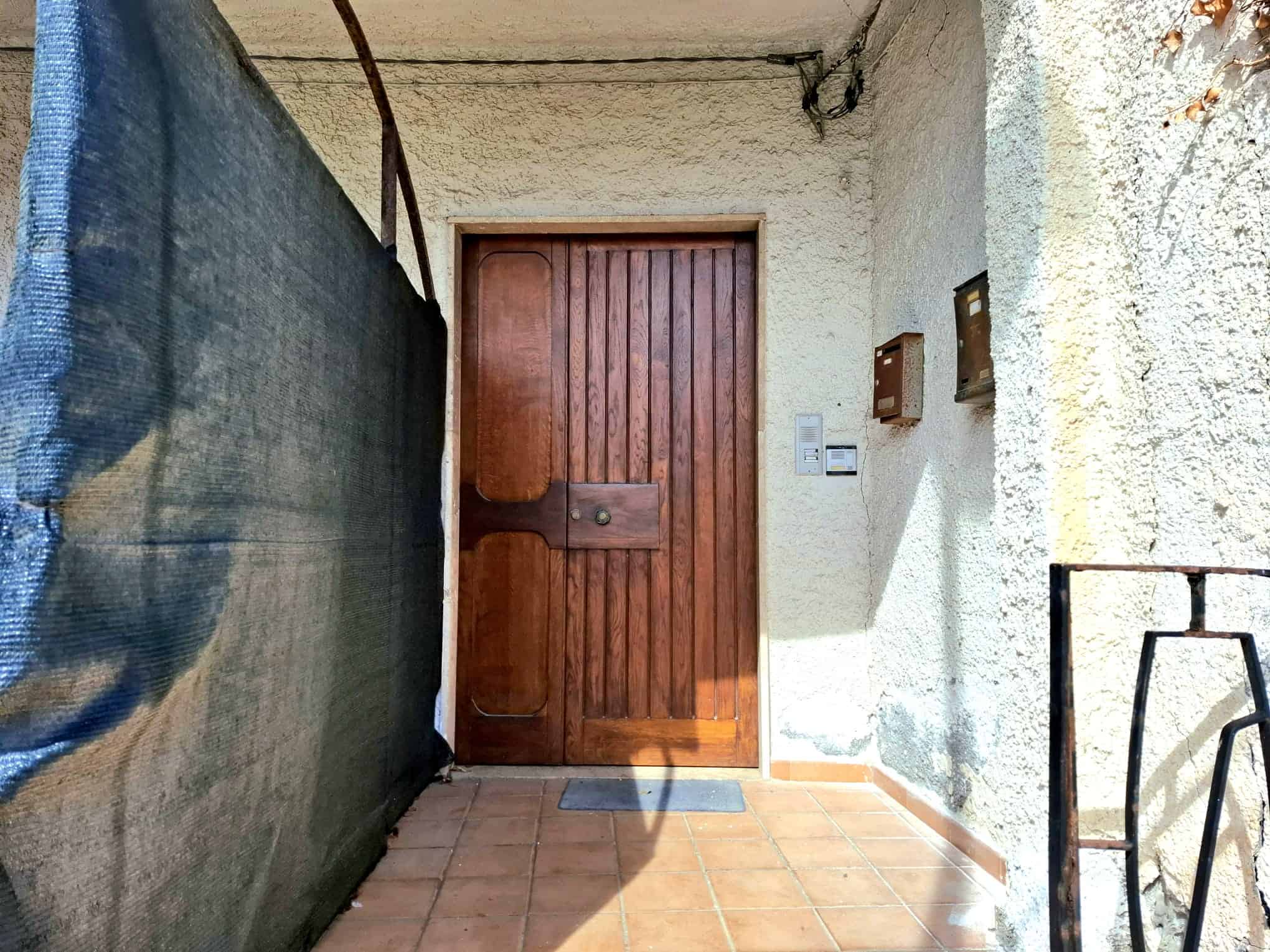 Porta d'ingresso in legno rustico con dettagli classici, accesso a appartamento in zona tranquilla e ben abitata - NextCasa, servizi immobiliari in Italia.
