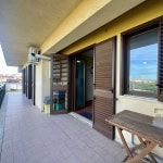Balcone di un appartamento in un complesso residenziale, con finestre con persiane in legno, spazio all'aperto con vista sulla città e arredi semplici.